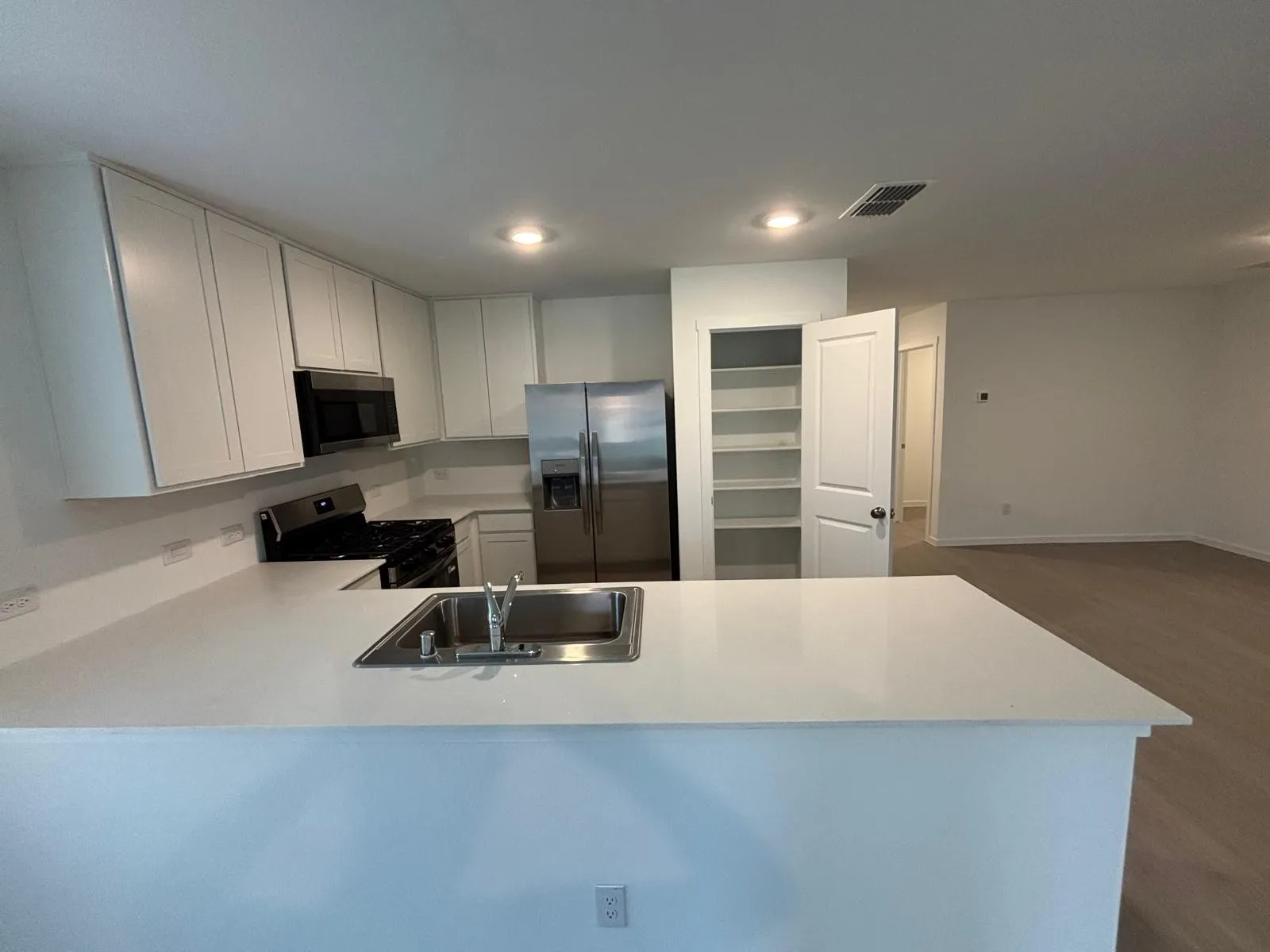 Modern kitchen featuring white shaker cabinetry, light-toned countertops, and stainless steel appliances