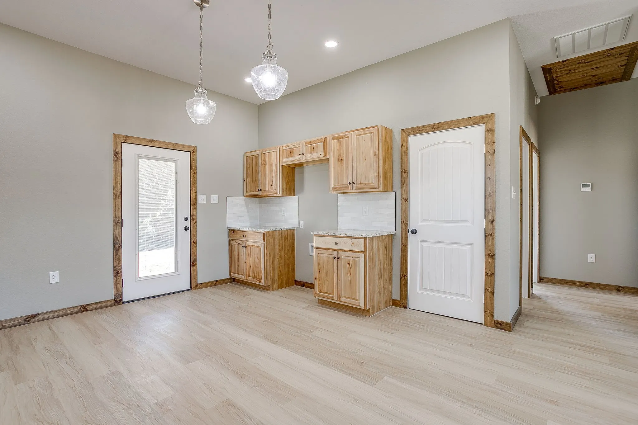 Pantry and Wood-finish flooring, natural wood cabinetry, pendant lighting, stone countertops, and a white paneled door