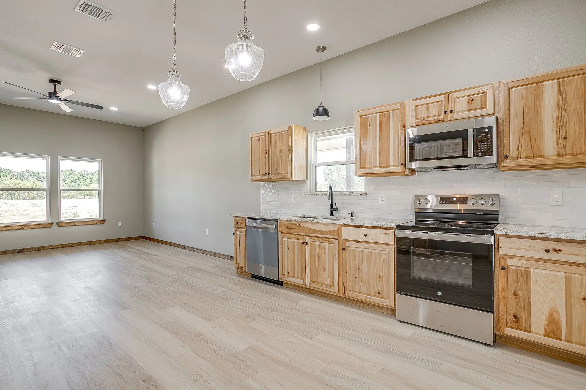 Open-concept living space featuring wood-finish flooring, recessed lighting, and a ceiling fan