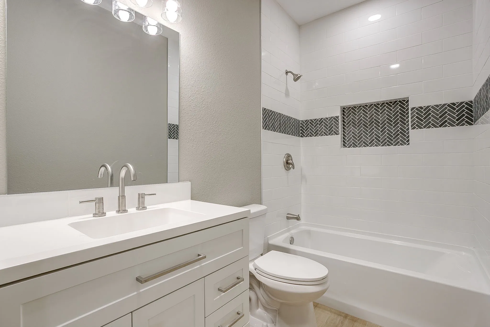 White vanity with brushed nickel hardware, integrated rectangular sink, and two-handle faucet