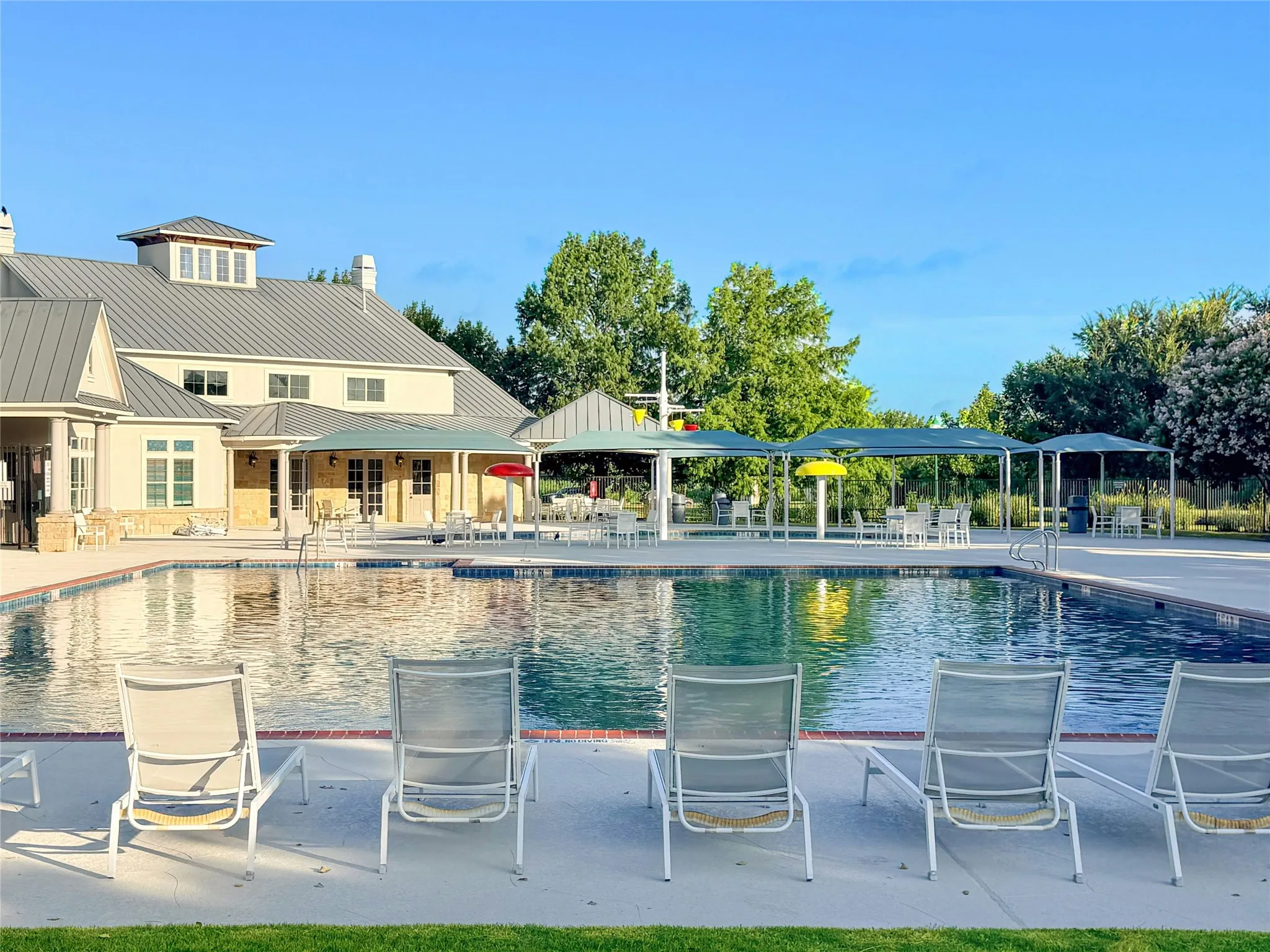 Sparkling Pool Surrounded by Concrete Decking, and Mature Landscaping.