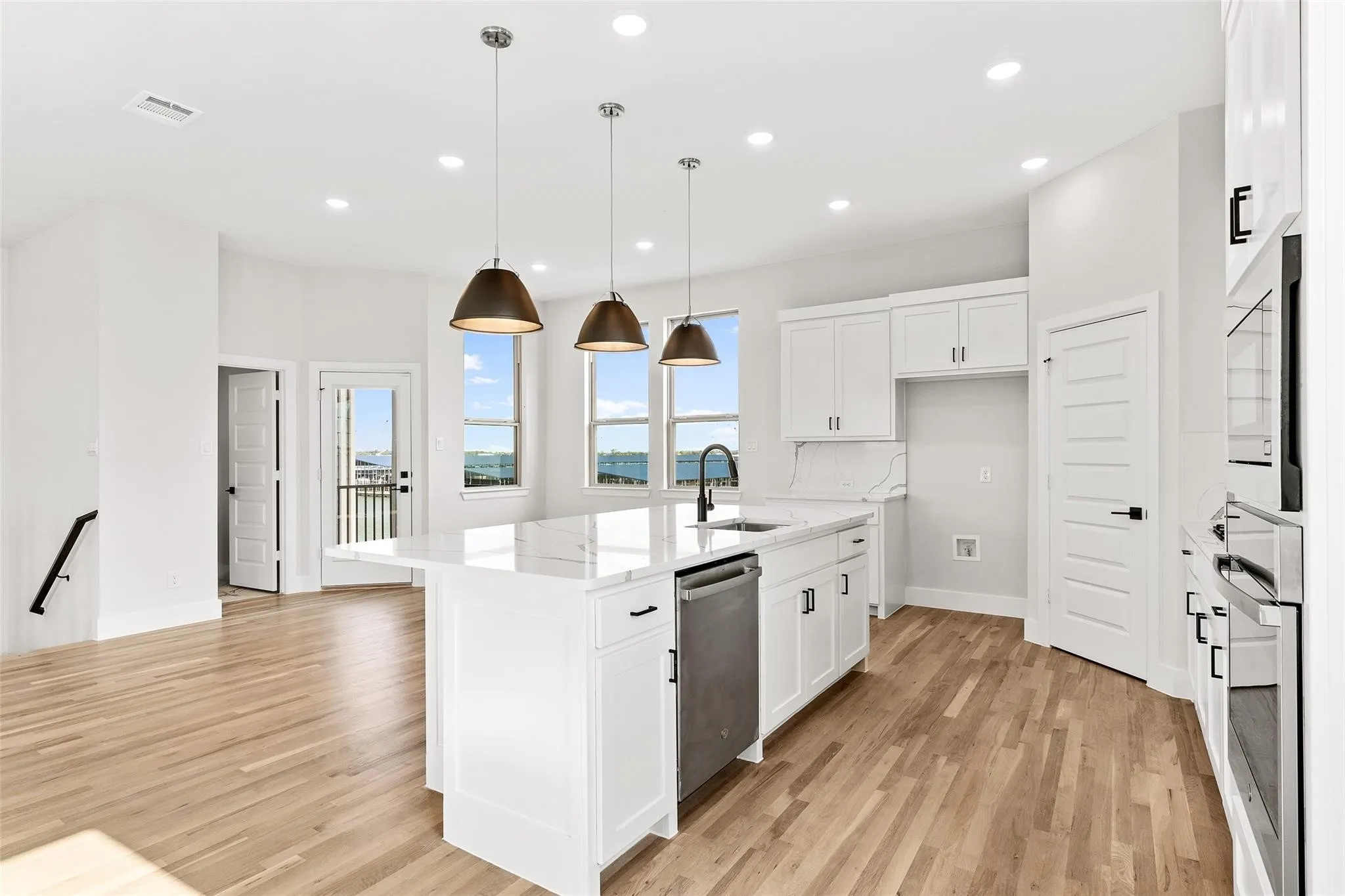 Oversized kitchen island with pendant lighting open to living area perfect for entertaining. Stainless appliances with gas cooktop