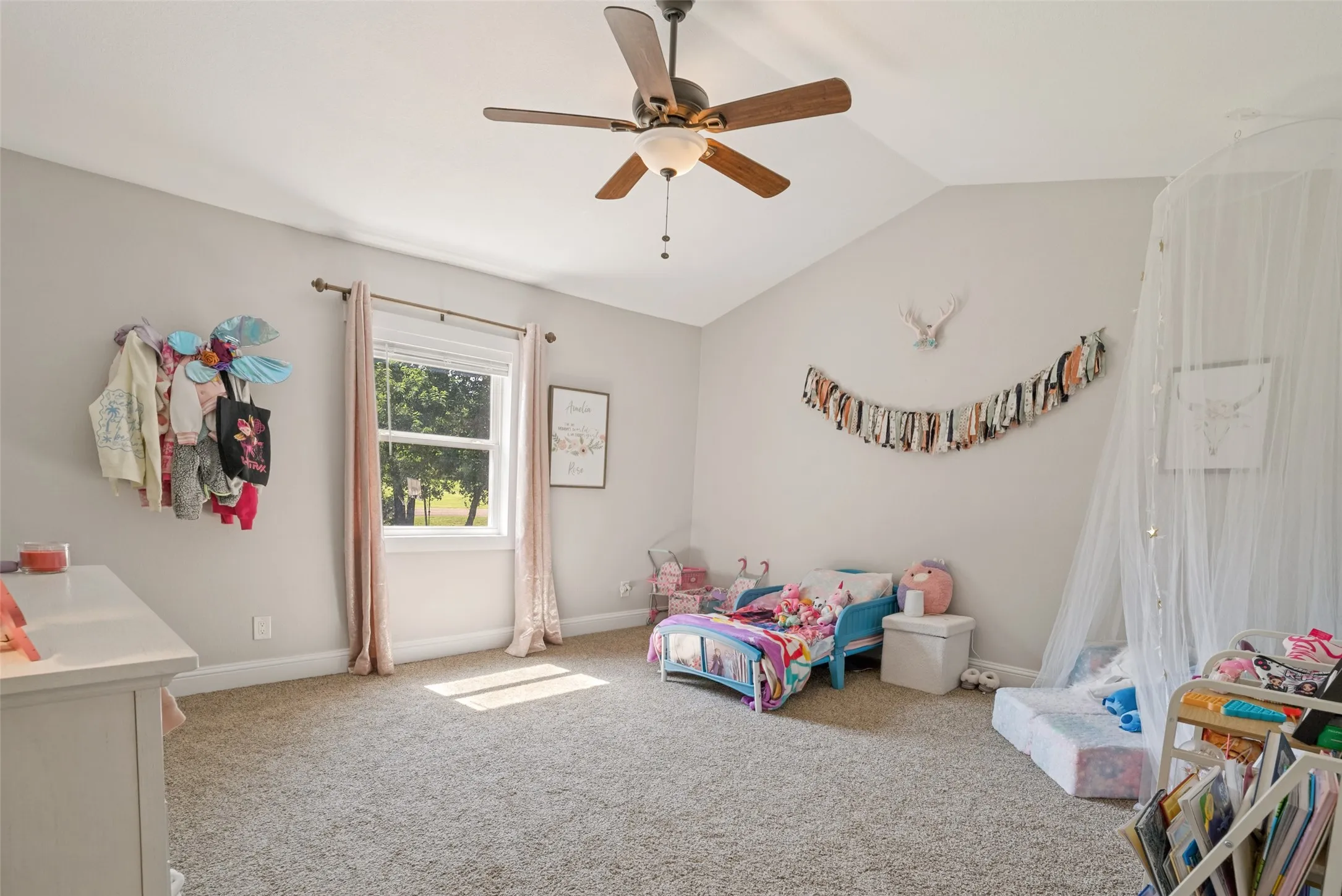 Carpeted room featuring a vaulted ceiling and a ceiling fan with integrated lighting