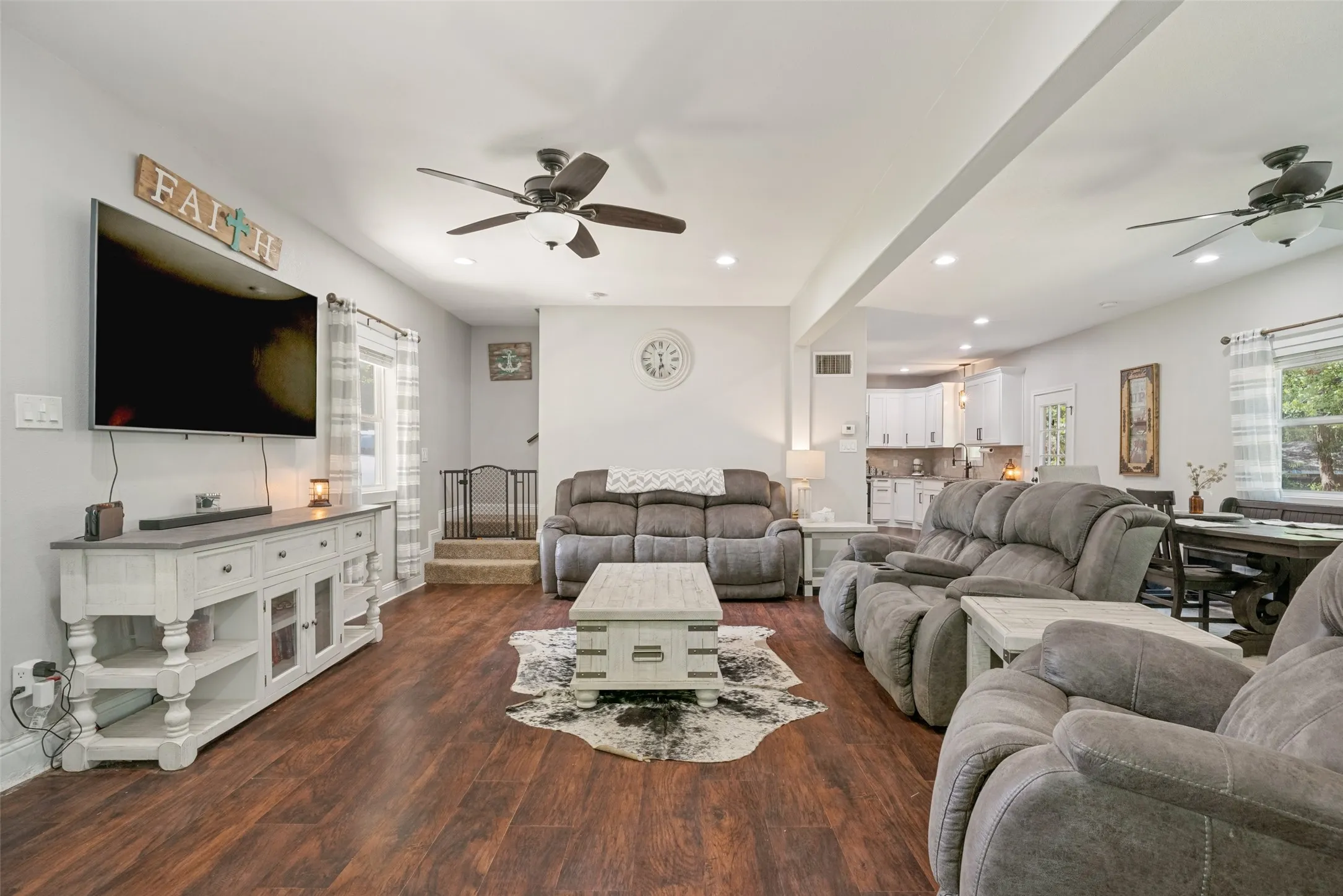 Spacious living area featuring rich wood-finish flooring, recessed lighting, and ceiling fans