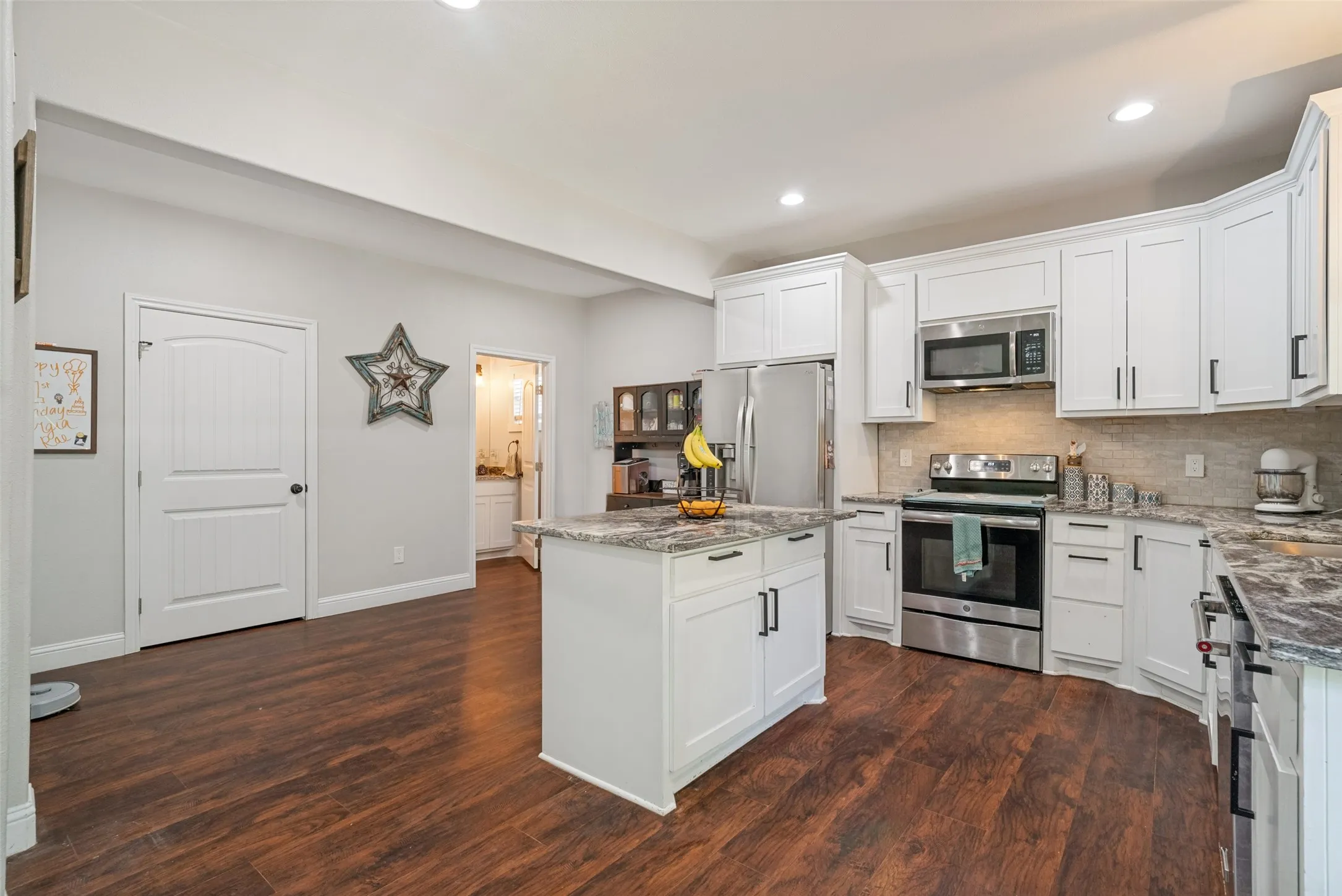 Modern kitchen featuring white cabinetry, stainless steel appliances, a center island with countertop, wood-finish flooring, and recessed lighting