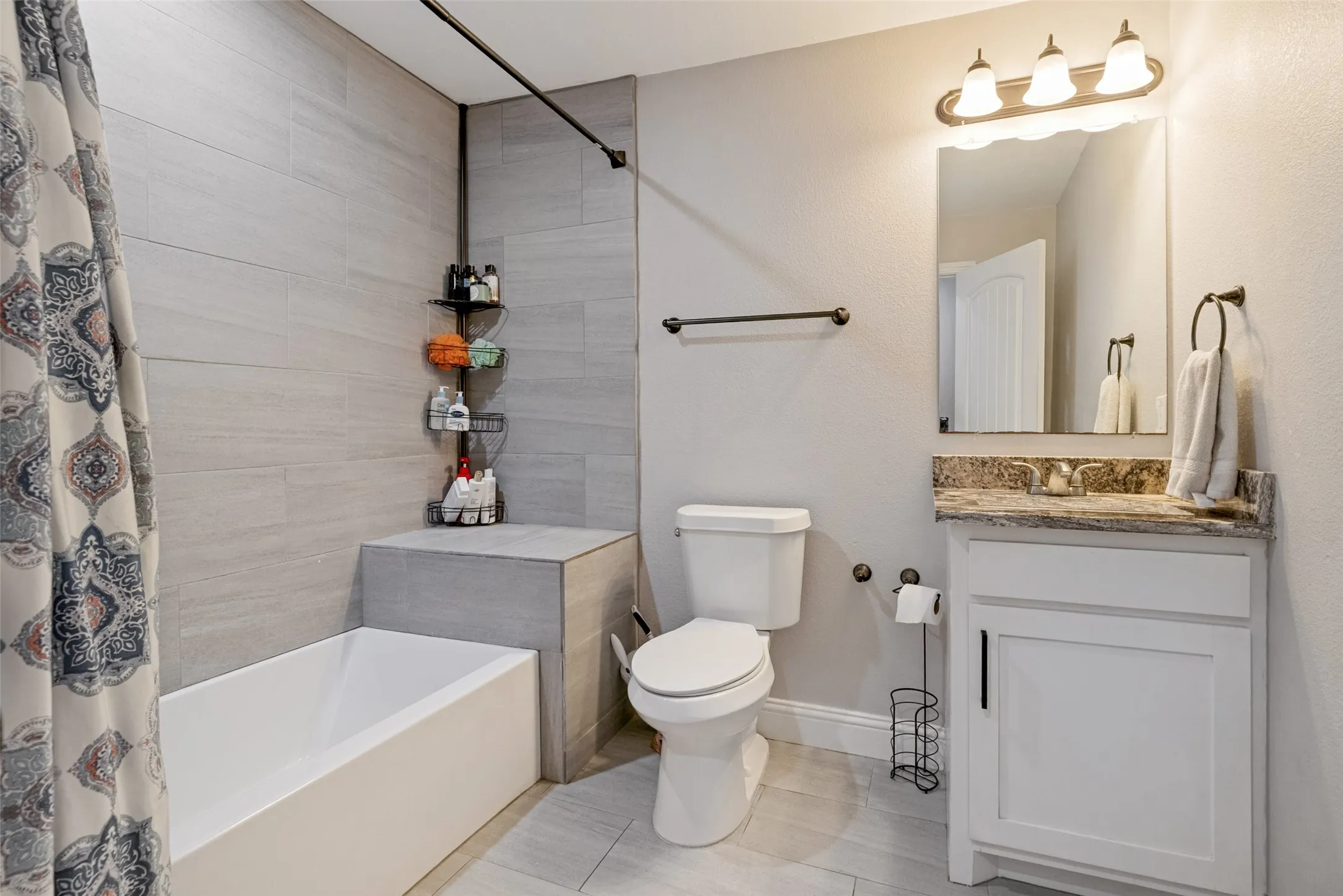 Full bathroom featuring a white bathtub, light-toned tile shower surround, and a coordinating floor