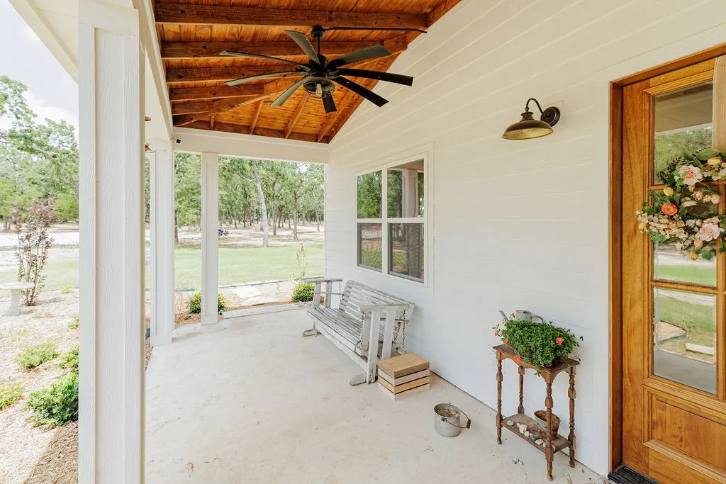 covered front porch with wood-finish vaulted ceiling and ceiling fan, hardy backer siding