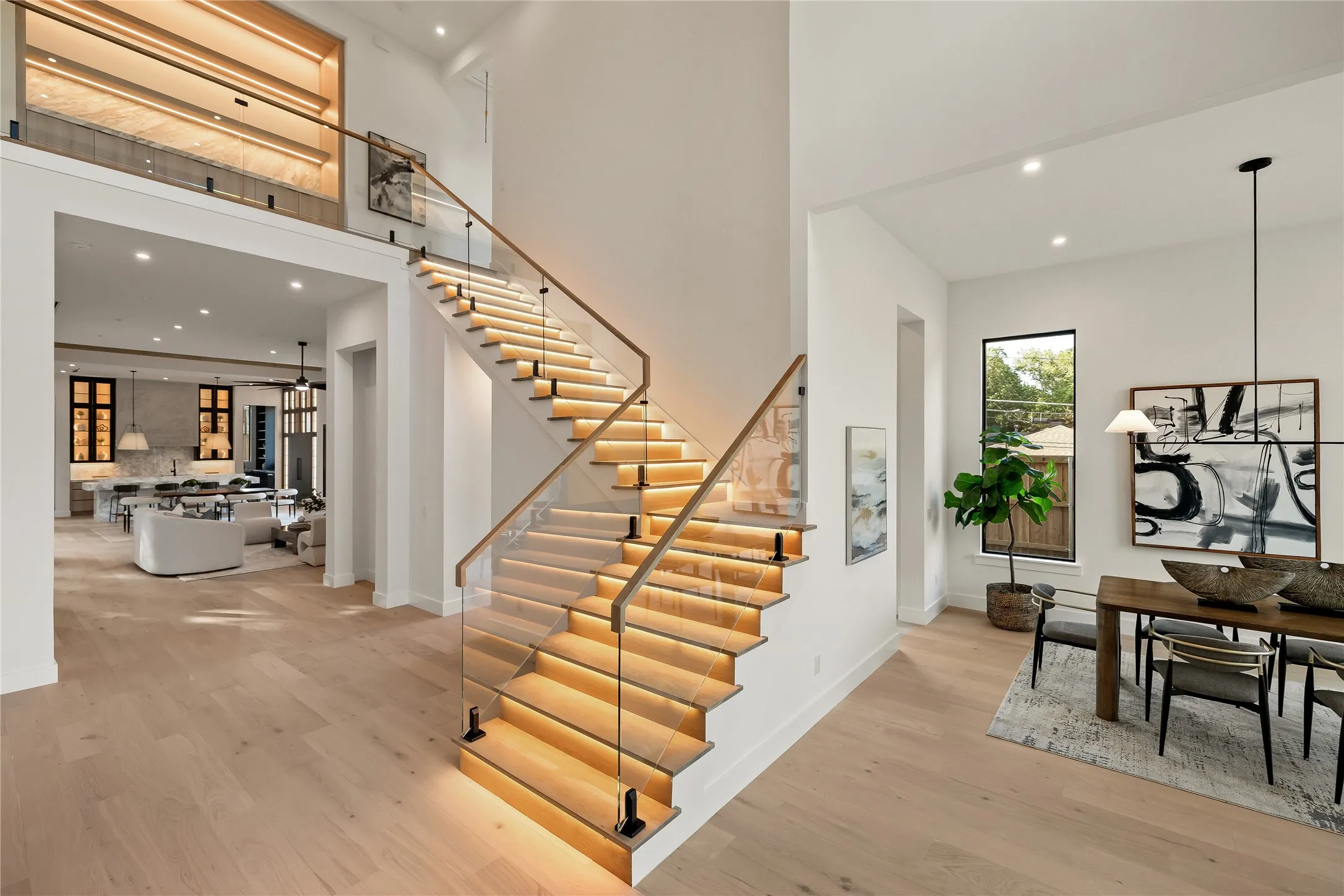Contemporary staircase featuring illuminated treads and glass railings with wooden handrails