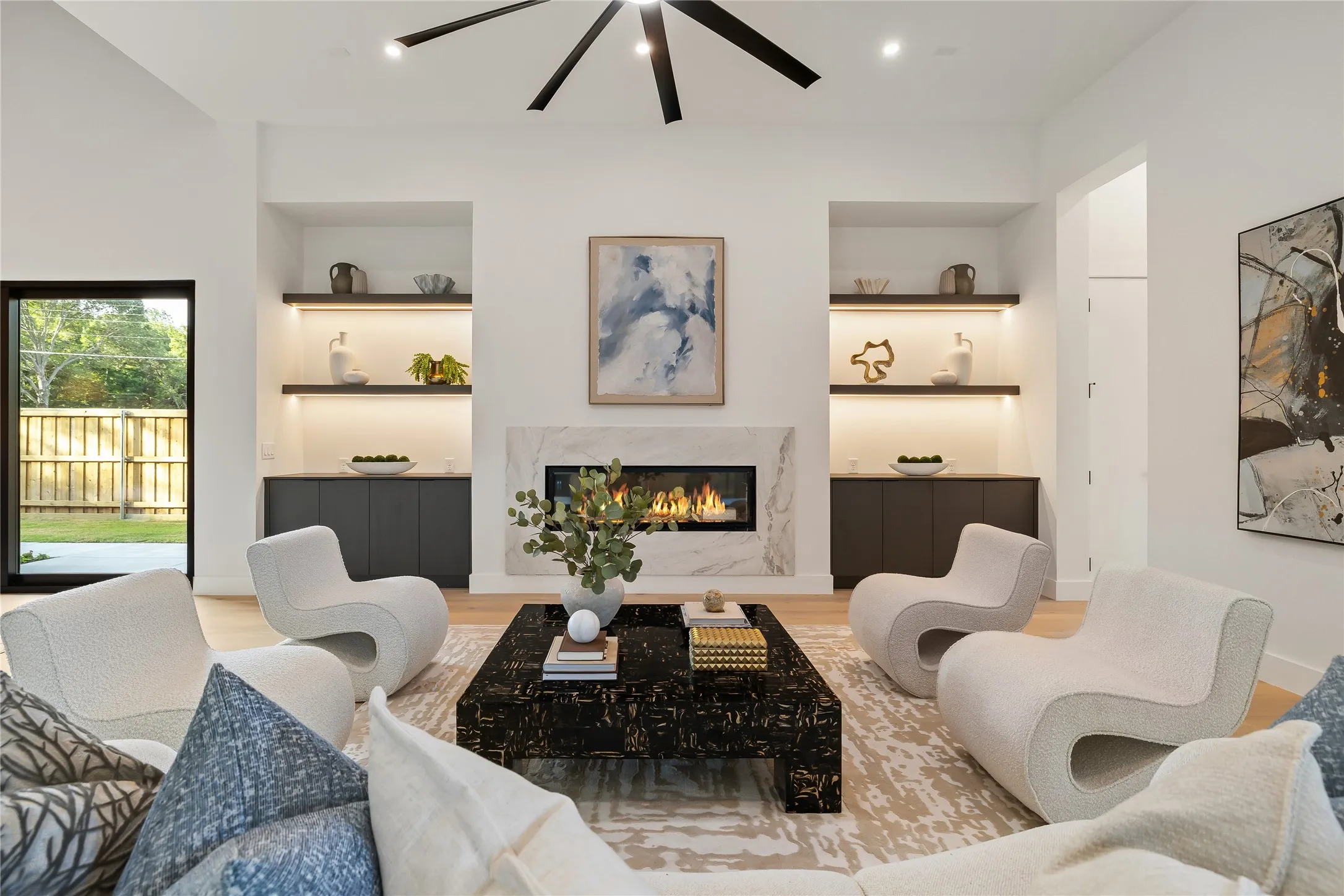 Living space featuring a linear gas fireplace with a stone surround, integrated built-in shelving with accent lighting, dark built-in cabinetry, and wood-finish flooring