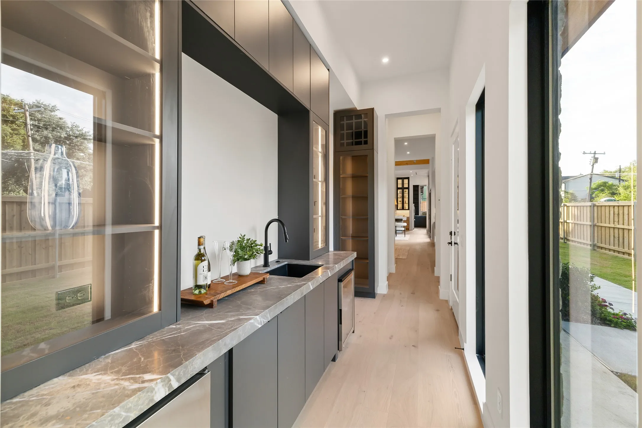 Wet bar featuring a dark stone countertop, integrated sink with matte black faucet, and under-counter refrigeration