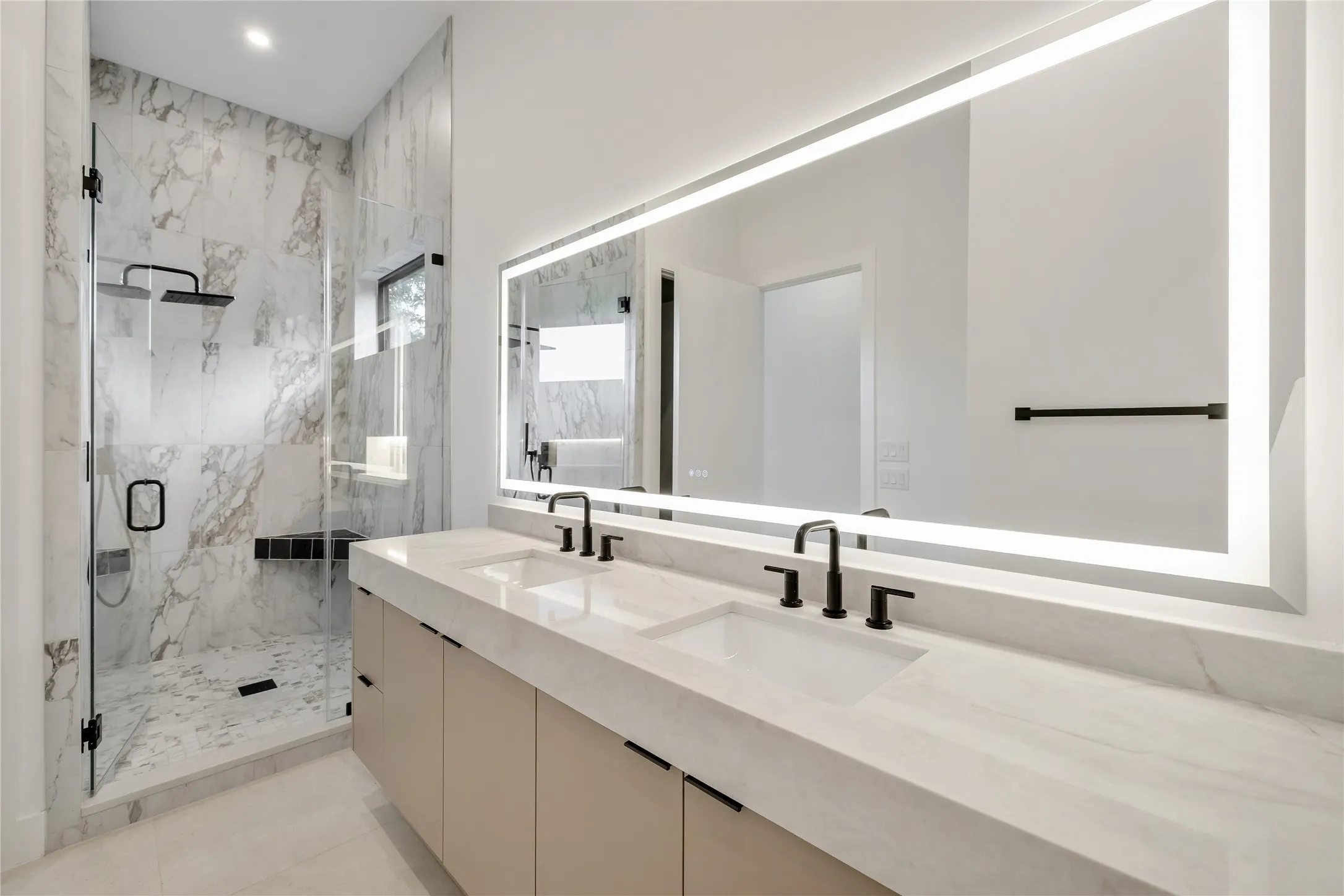 Dual vanity with integrated sinks and matte black fixtures, set beneath an illuminated mirror