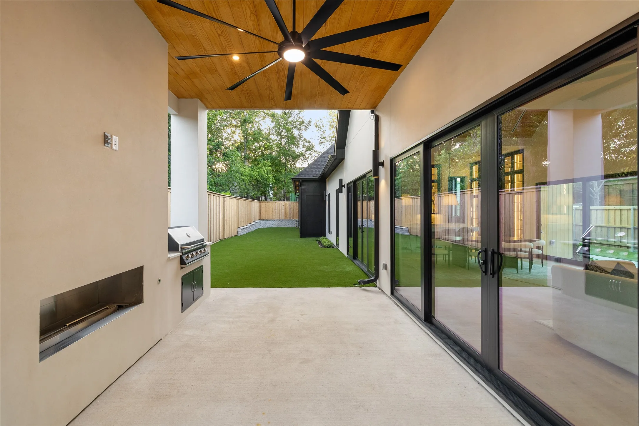 Covered patio featuring an integrated grill station, wood-finish ceiling with a ceiling fan, and extensive sliding glass doors