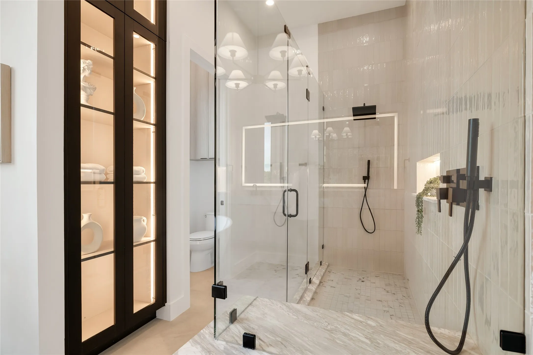 Glass-enclosed shower with matte black fixtures, integrated shelving, and textured tile walls