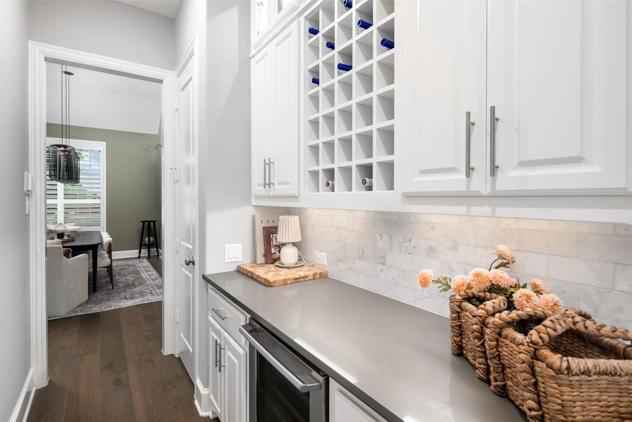 Perfectly positioned between the kitchen and formal dining room, this elegant serving area is designed for effortless entertaining with custom cabinetry, expansive quartz countertops, a built-in beverage refrigerator, and a dedicated wine rack that blends style with everyday functionality.