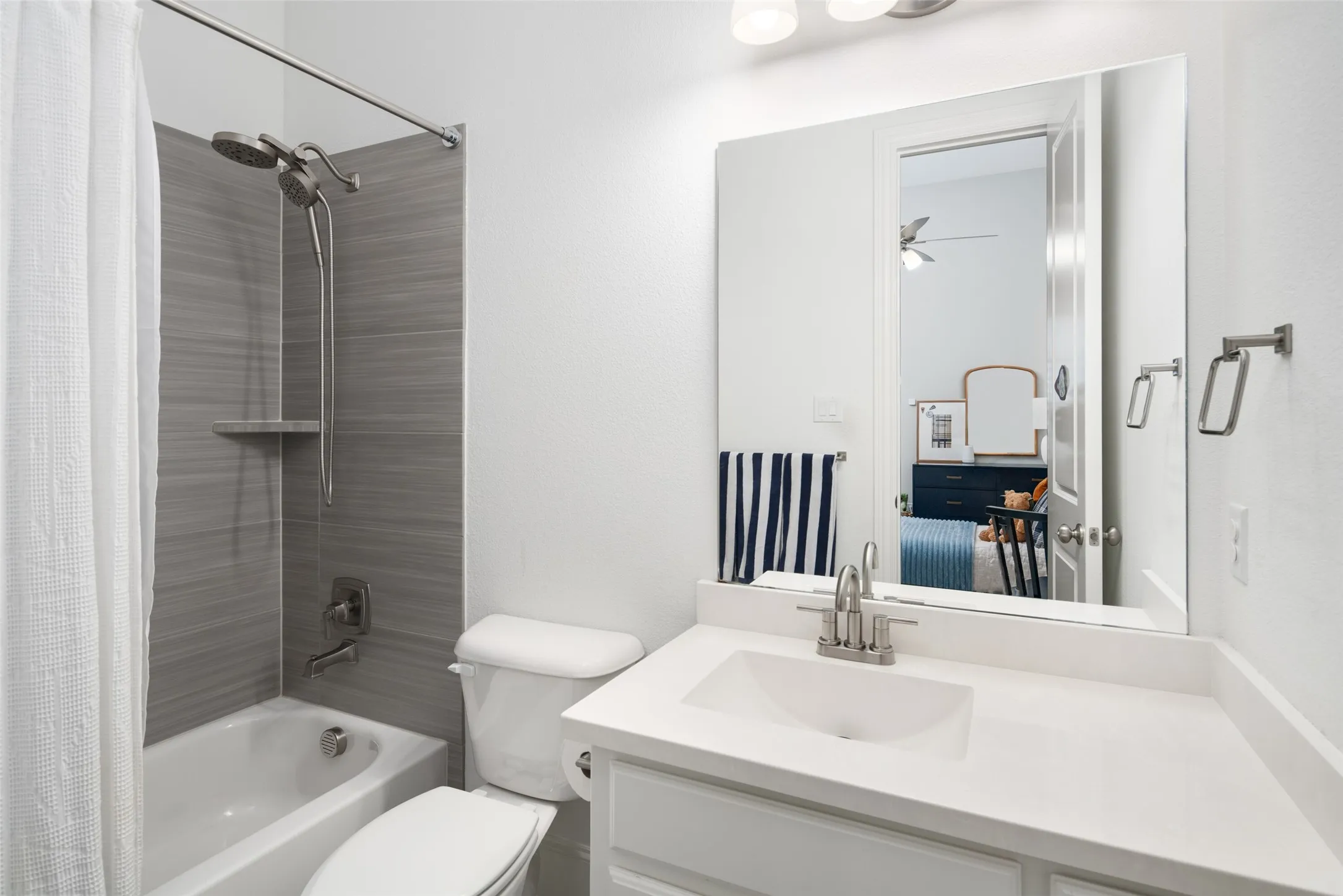 The private ensuite bathroom features a spacious vanity with generous counter space and storage, paired with a shower/tub combination accented by designer tile surrounds.