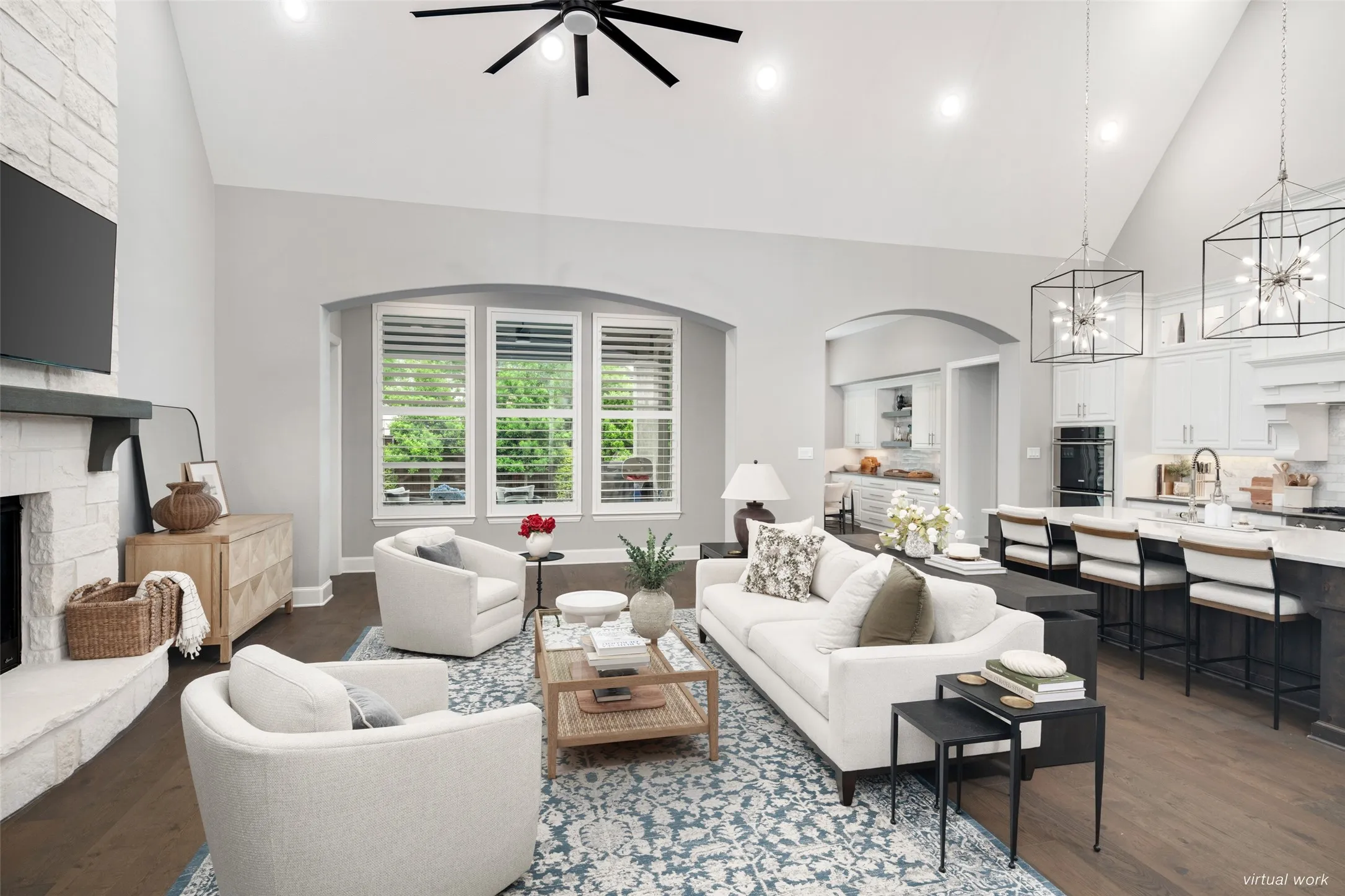 Designed with effortless flow in mind, the open-concept layout seamlessly connects the chef's kitchen, spacious living room, and breakfast nook beneath soaring vaulted ceilings. Rich wide plank wood floors, dramatic designer lighting, and walls of windows with plantation shutters create a bright, inviting atmosphere that's perfectly suited for everyday living, entertaining, and gathering with family and friends.