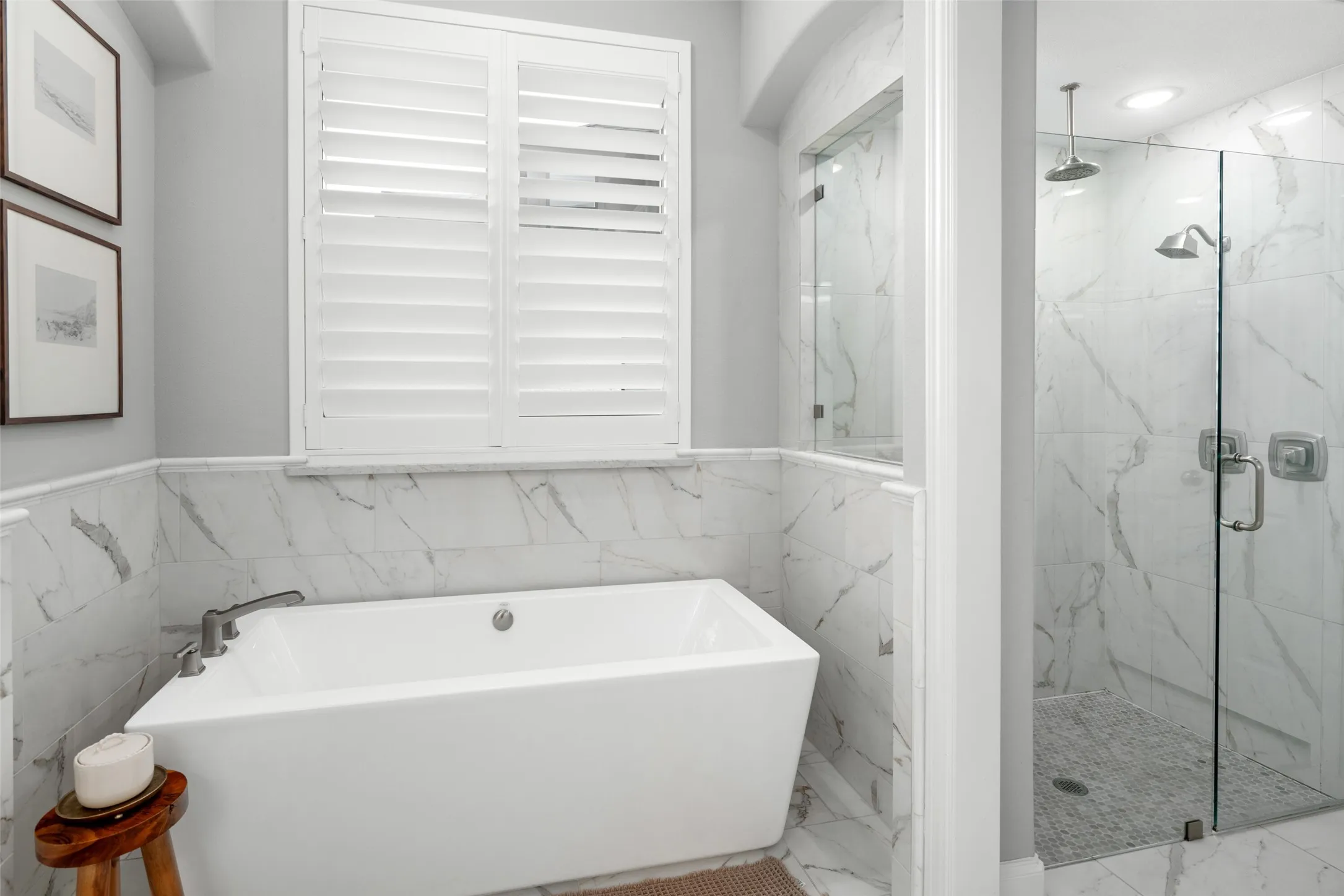 The spa-inspired primary bath offers a luxurious retreat with a freestanding soaking tub surrounded by upgraded floor-to-ceiling designer tile, creating the perfect place to unwind. A separate walk-in shower with frameless glass enclosure and elegant tile finishes completes this sophisticated space, blending timeless design with everyday luxury.
