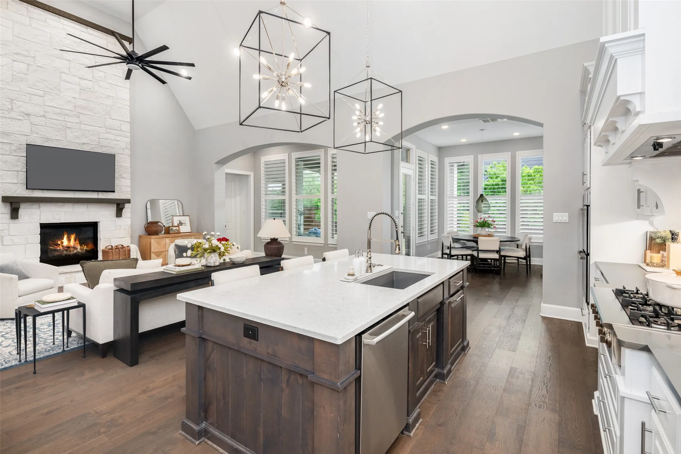The oversized quartz island serves as the heart of the home, featuring a large sink, upgraded pull-down faucet, built-in pull-out trash, and generous seating, while seamlessly connecting the kitchen, living room, and breakfast area to create an inviting space for family and guests alike.