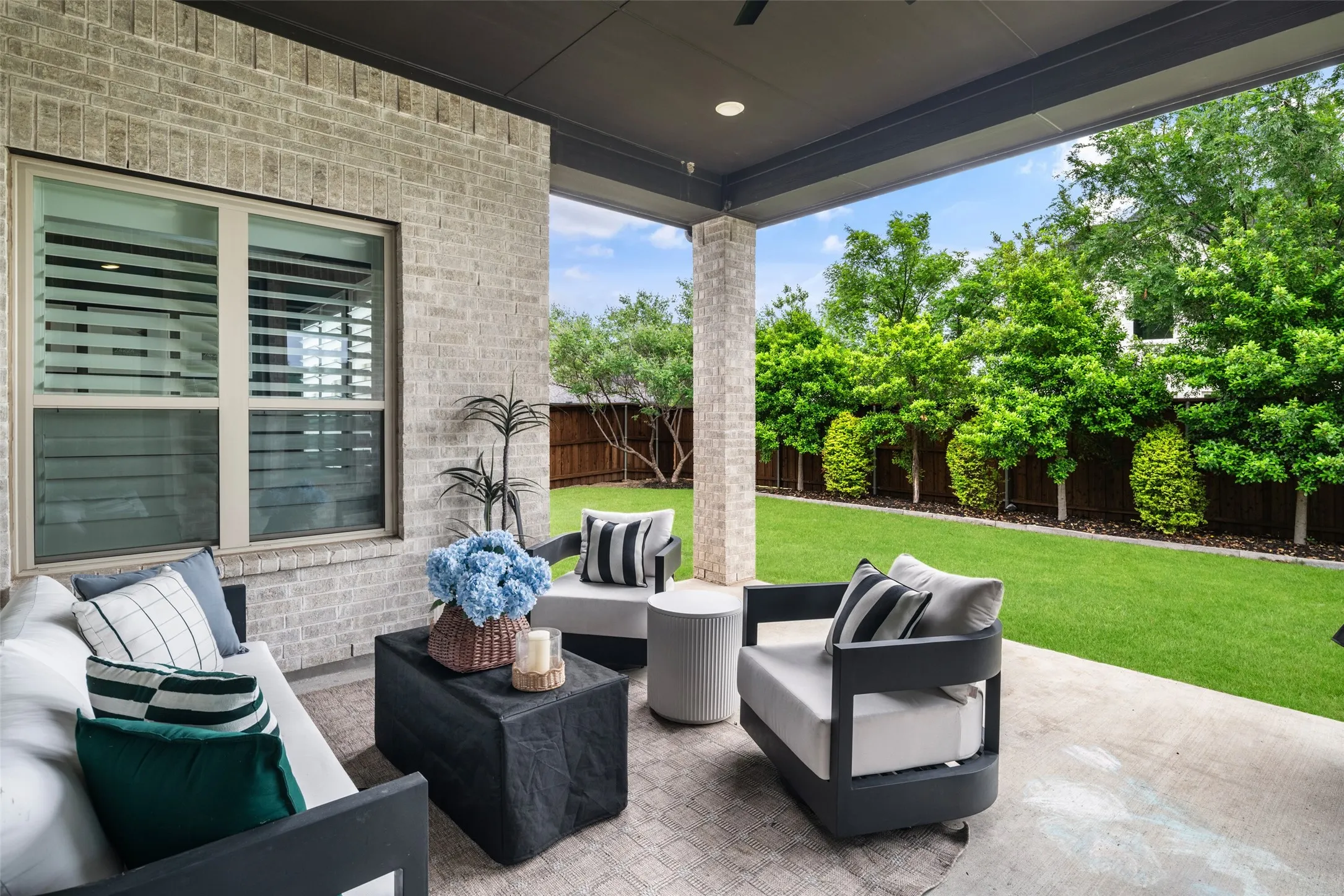 Overlooking the beautifully landscaped backyard with lush green space and mature privacy trees, this inviting outdoor retreat is the perfect place to enjoy morning coffee, evening gatherings, or peaceful Texas sunsets.