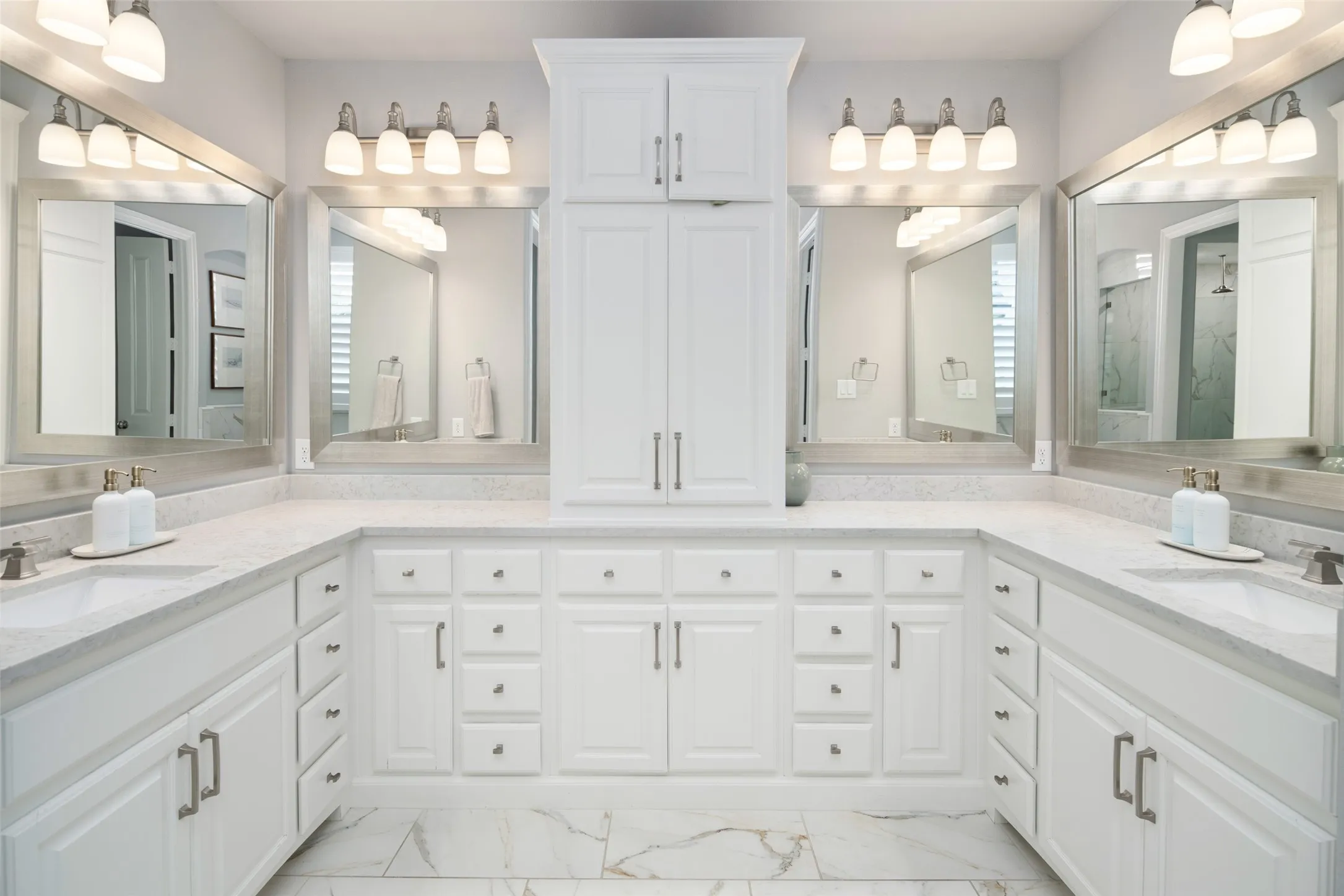 Indulge in the spa-inspired primary bath featuring an expansive U-shaped dual vanity with abundant cabinetry and drawer storage, a floor-to-ceiling linen cabinet, elegant framed mirrors, upgraded designer lighting, and luxurious quartz countertops. Thoughtfully designed with exceptional storage and timeless finishes, this sophisticated retreat blends everyday functionality with refined luxury.