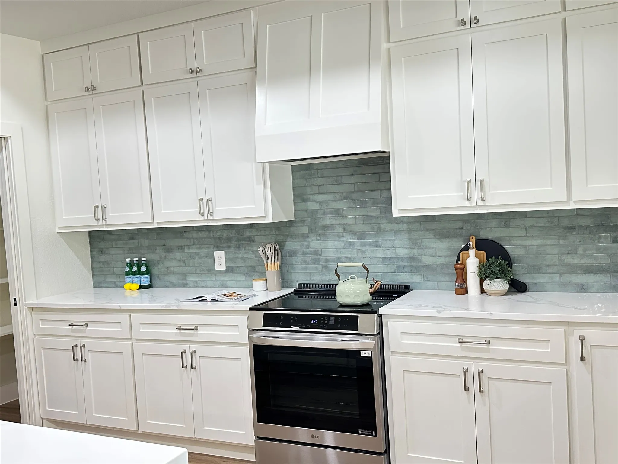 Kitchen with tons of great finishes. Induction stove + extra features, beautiful backsplash greenish grey with grey grout accenting the grey in countertops. Look at those stainless steel handles and knobs!