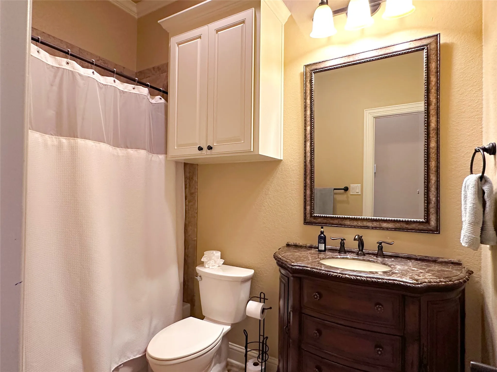 Bathroom featuring an ornate dark wood vanity with a stone countertop, a framed mirror, and a wall-mounted light fixture