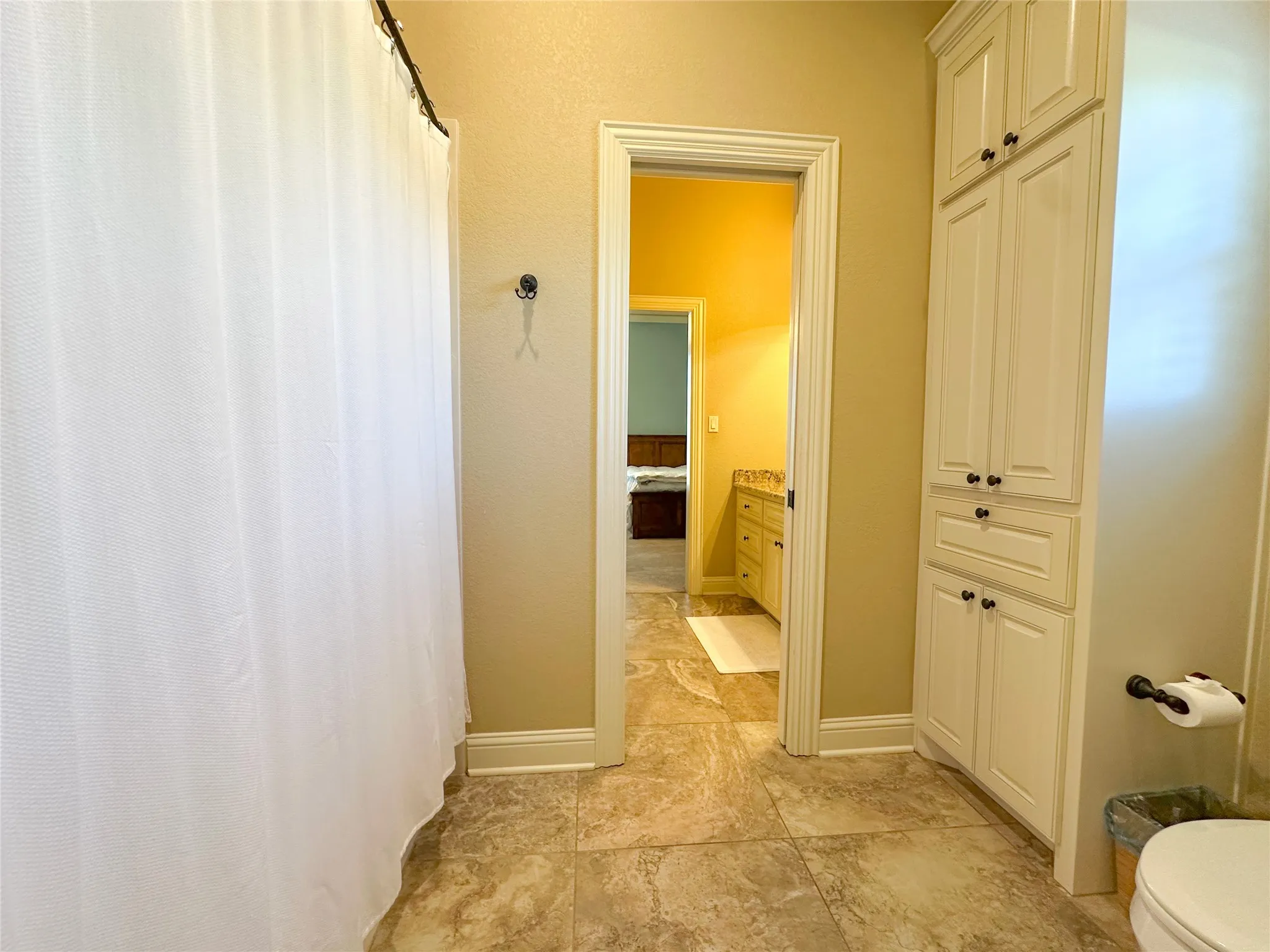 Bathroom with tile flooring, white shower curtain, and built-in white cabinetry