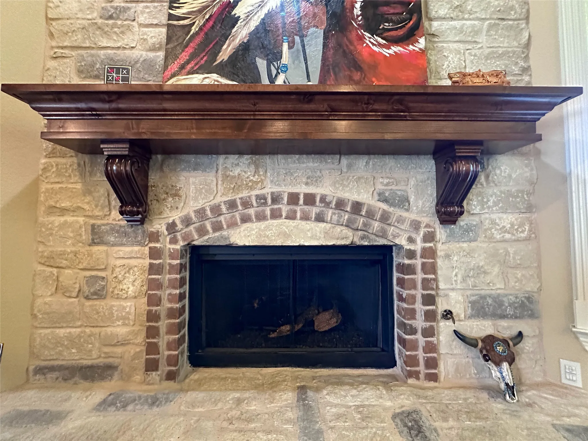 Stone fireplace featuring a brick arched firebox, substantial wood mantel with carved corbels, and a stone hearth