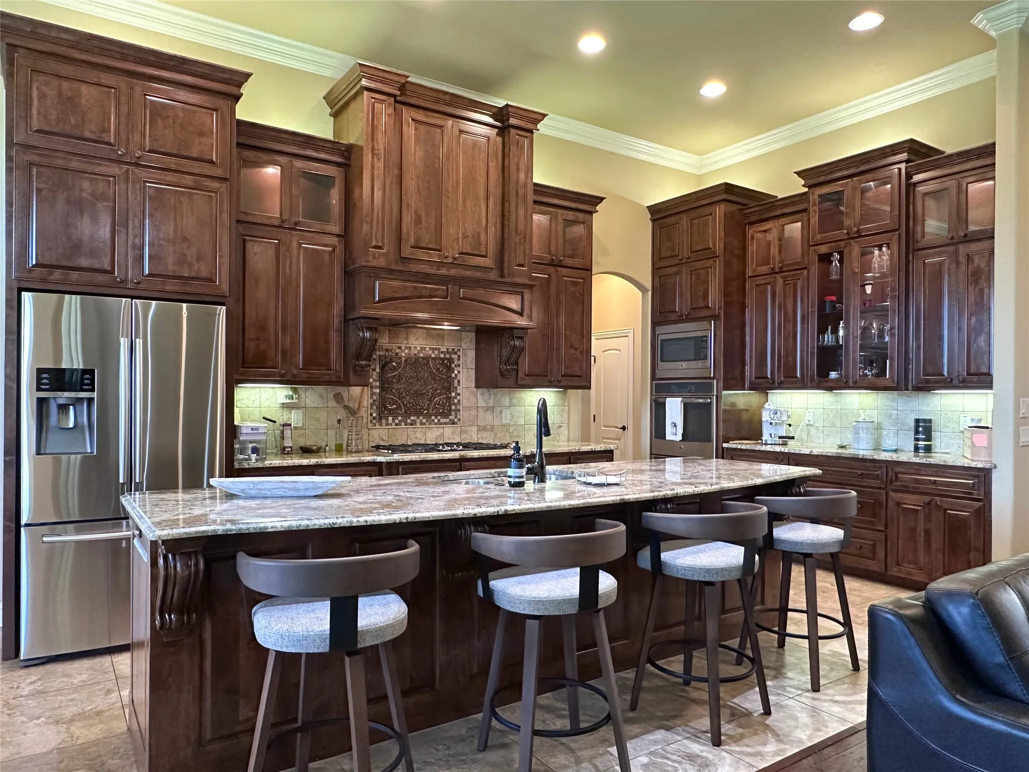 Kitchen featuring extensive dark wood cabinetry, a large kitchen island with counter seating, stainless steel appliances, and a decorative tile backsplash