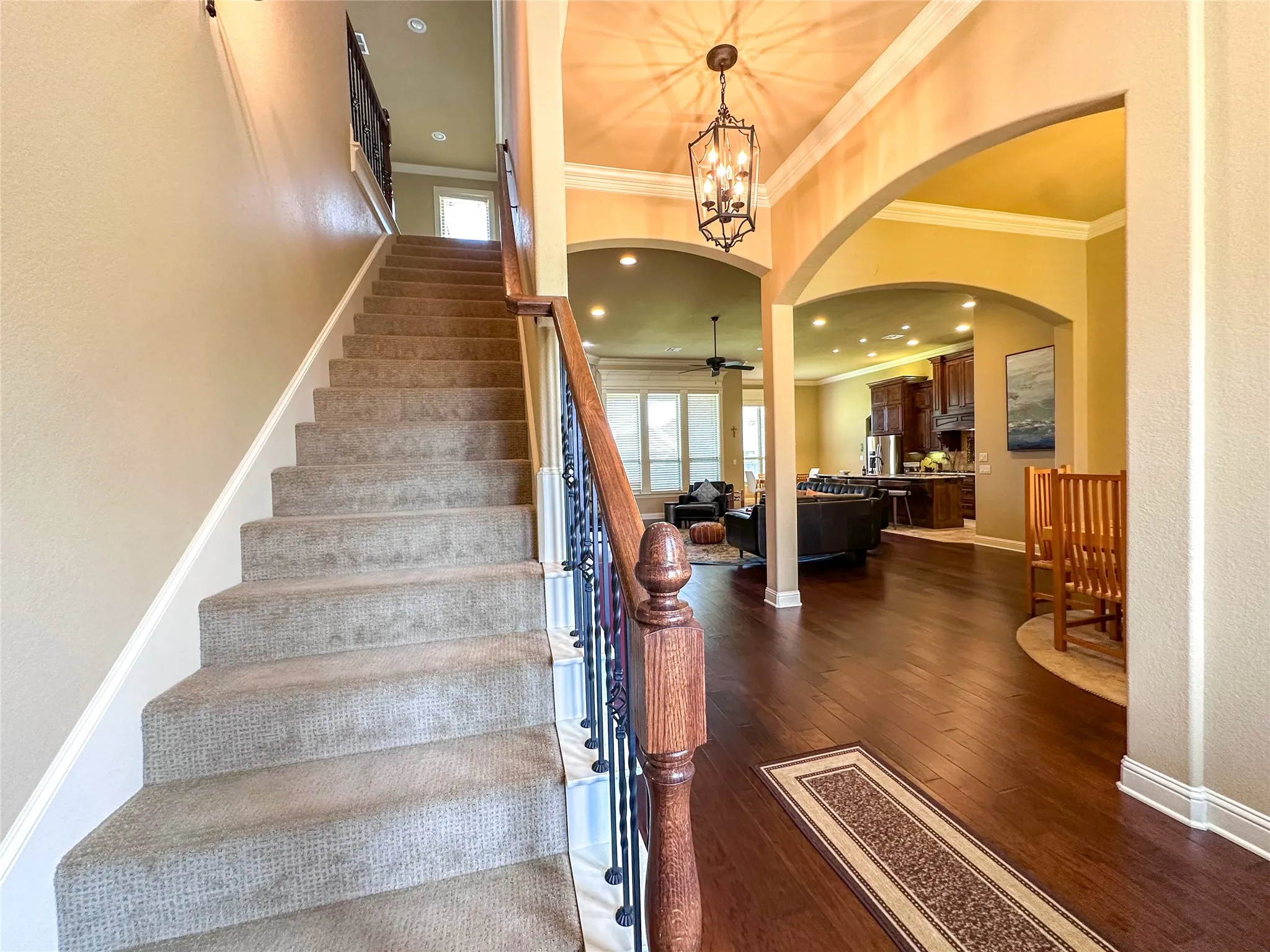 Grand entryway featuring a carpeted staircase with wrought iron balusters and a wood handrail