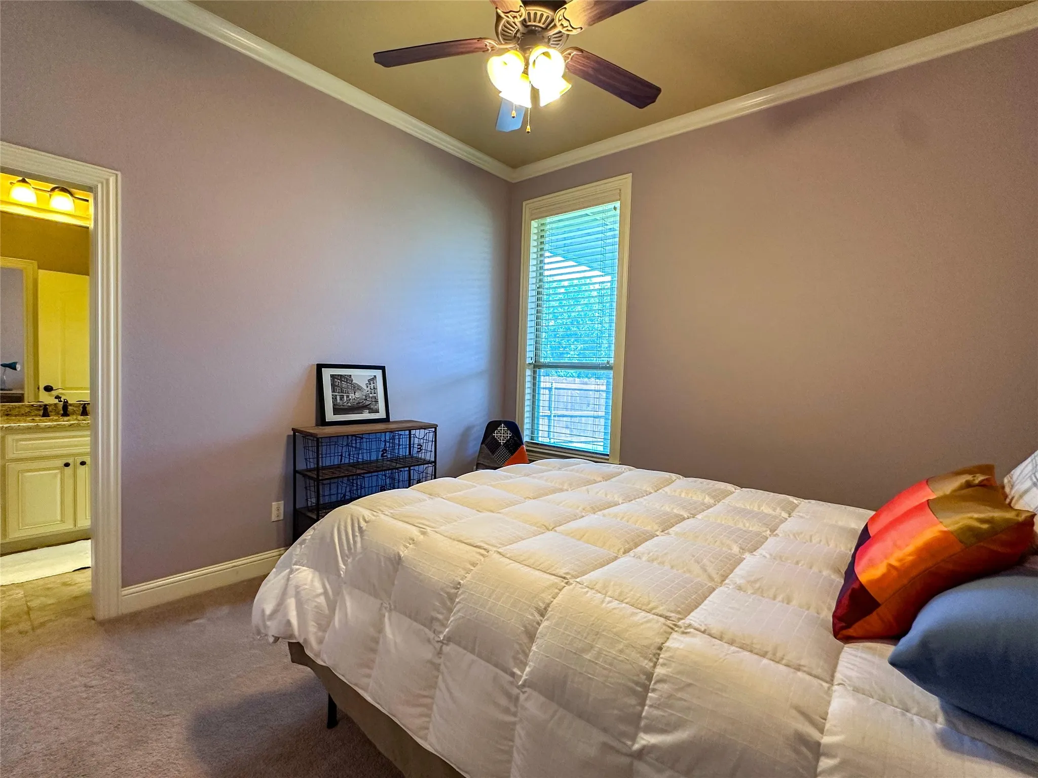 Bedroom featuring a ceiling fan with integrated lighting, crown molding, and a window with blinds