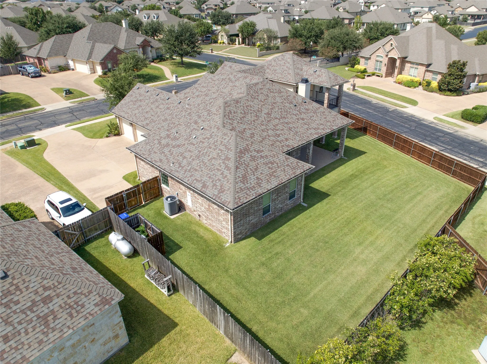 Expansive backyard featuring a manicured lawn, full perimeter privacy fencing, and a covered patio area