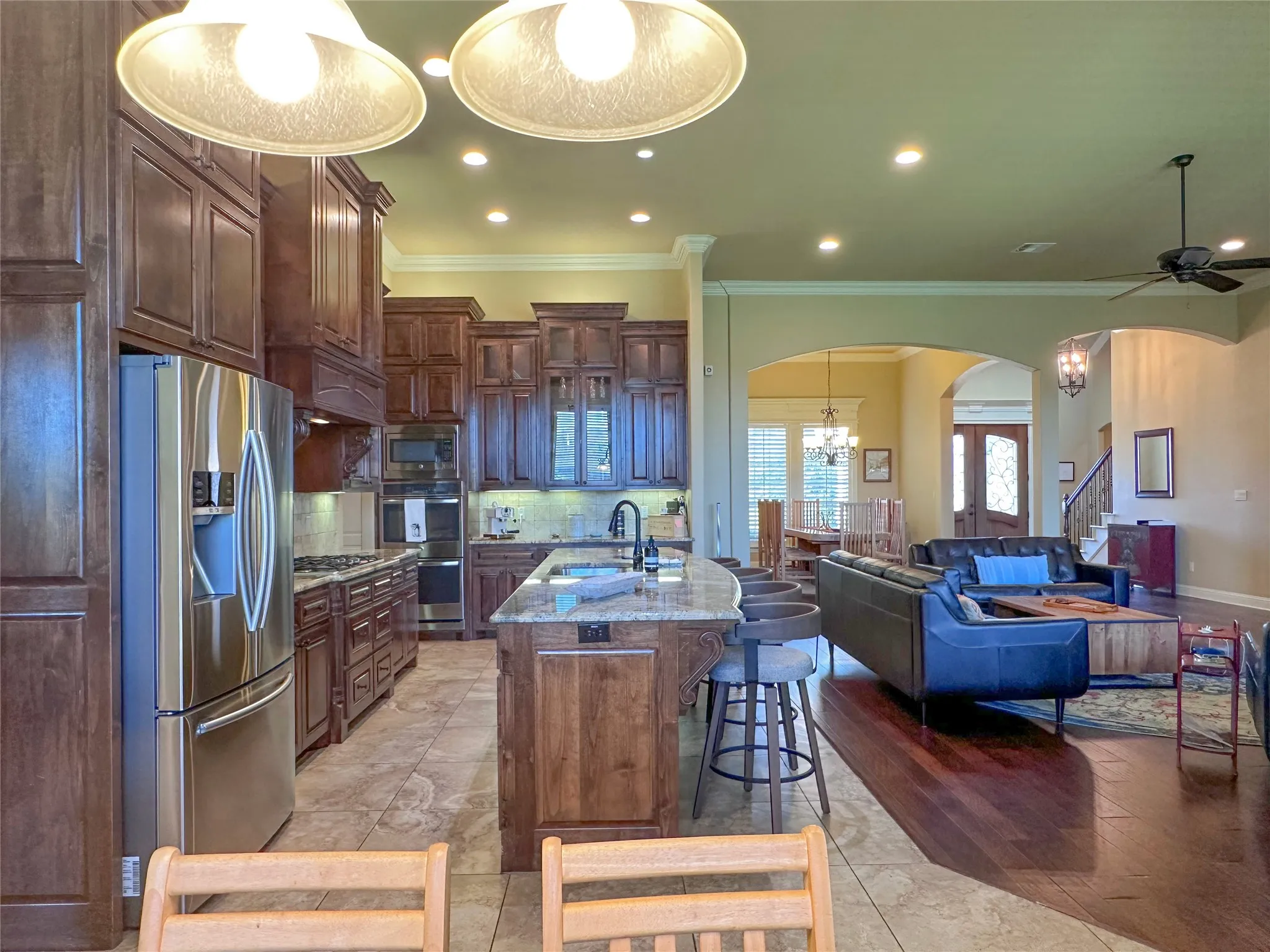 Kitchen featuring dark wood cabinetry, stainless steel appliances, a center island with a granite countertop, and recessed lighting