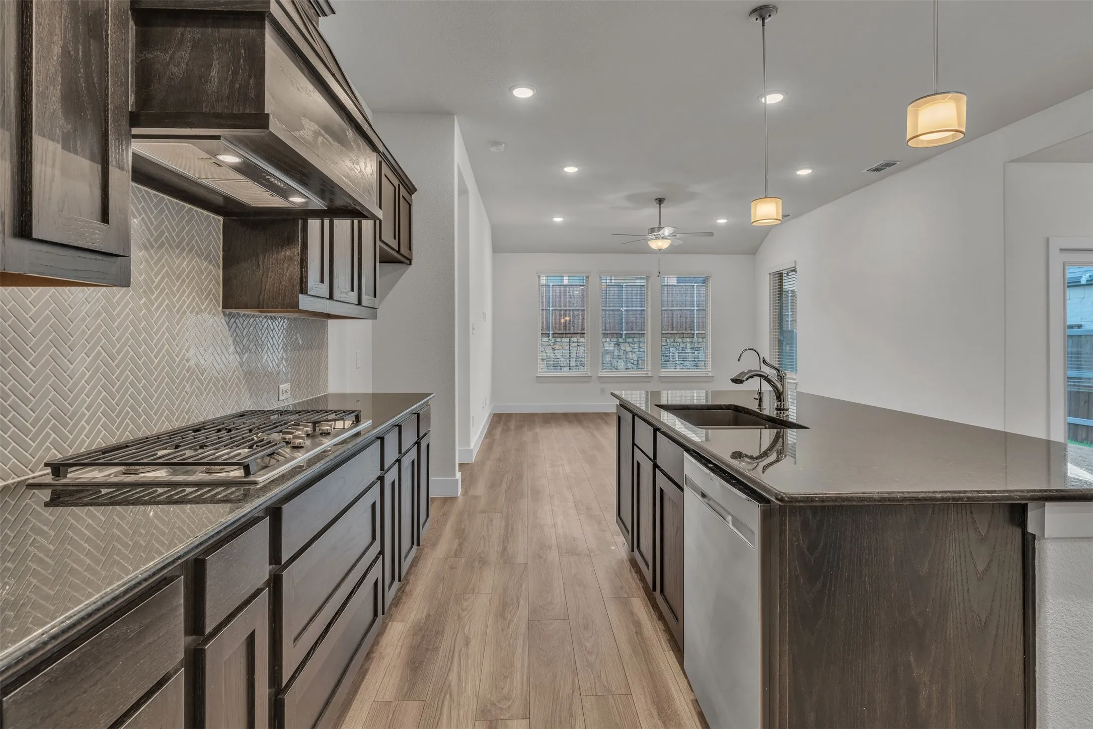 Kitchen at 5149 Cantle Ct in Fort Worth, Texas, Tarrant County, with large kitchen island, brown wooden cabinets, neutral herringbone backsplash, and separate cooktop.