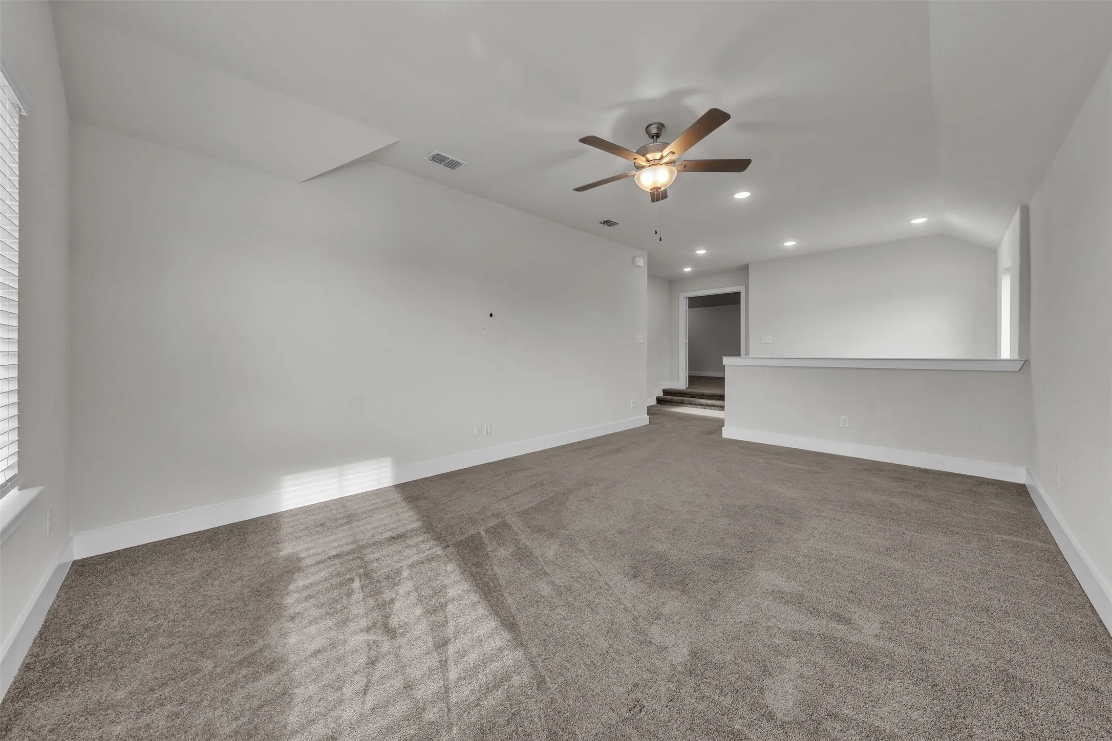 Family Room at 5149 Cantle Ct in Fort Worth, Texas, Tarrant County, with light colored carpet facing top of staircase and dedicated media room. Ceiling fan with dual switch. Located on second floor as a flex space or second living space.