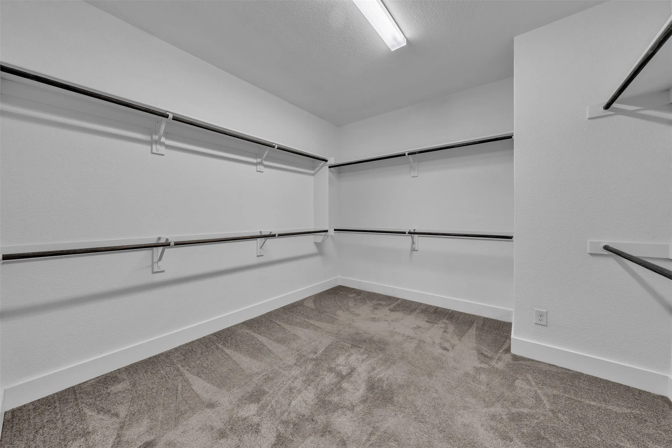 Primary Closet at 5149 Cantle Ct in Fort Worth, Texas, Tarrant County, with light colored carpet and clothing rods double stacked on three walls and built in shelving (not pictured). HUGE!