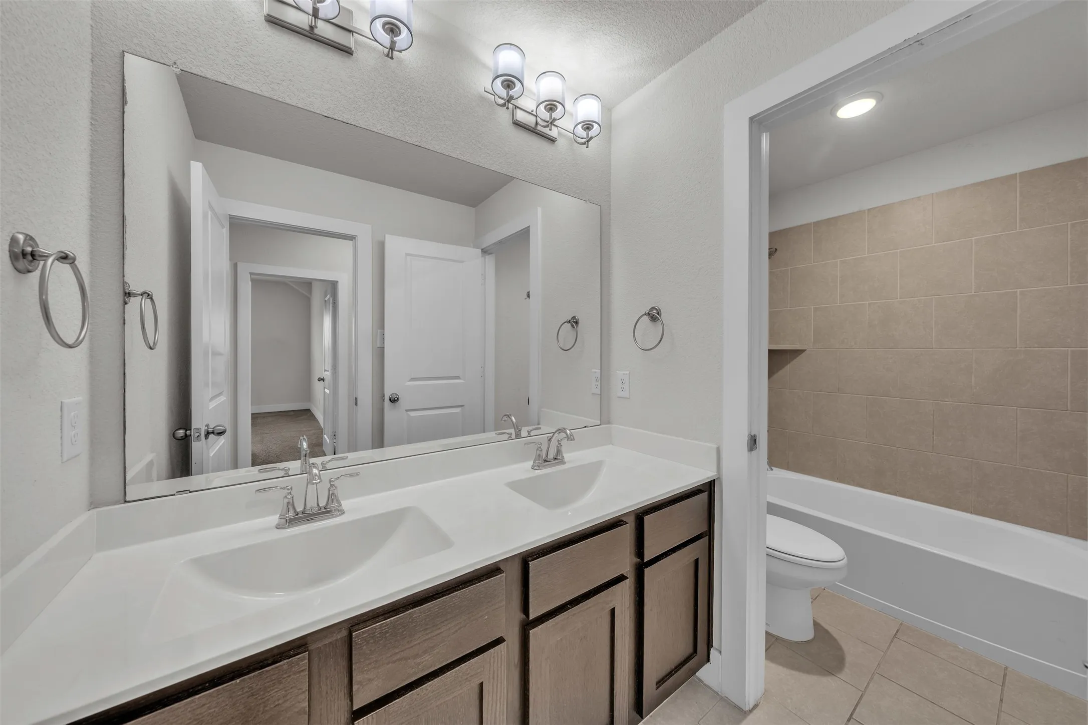 Bathroom at 5149 Cantle Ct in Fort Worth, Texas, Tarrant County, with door separating toilet and combo bathtub/shower. Dual sinks and plenty of cabinet storage.