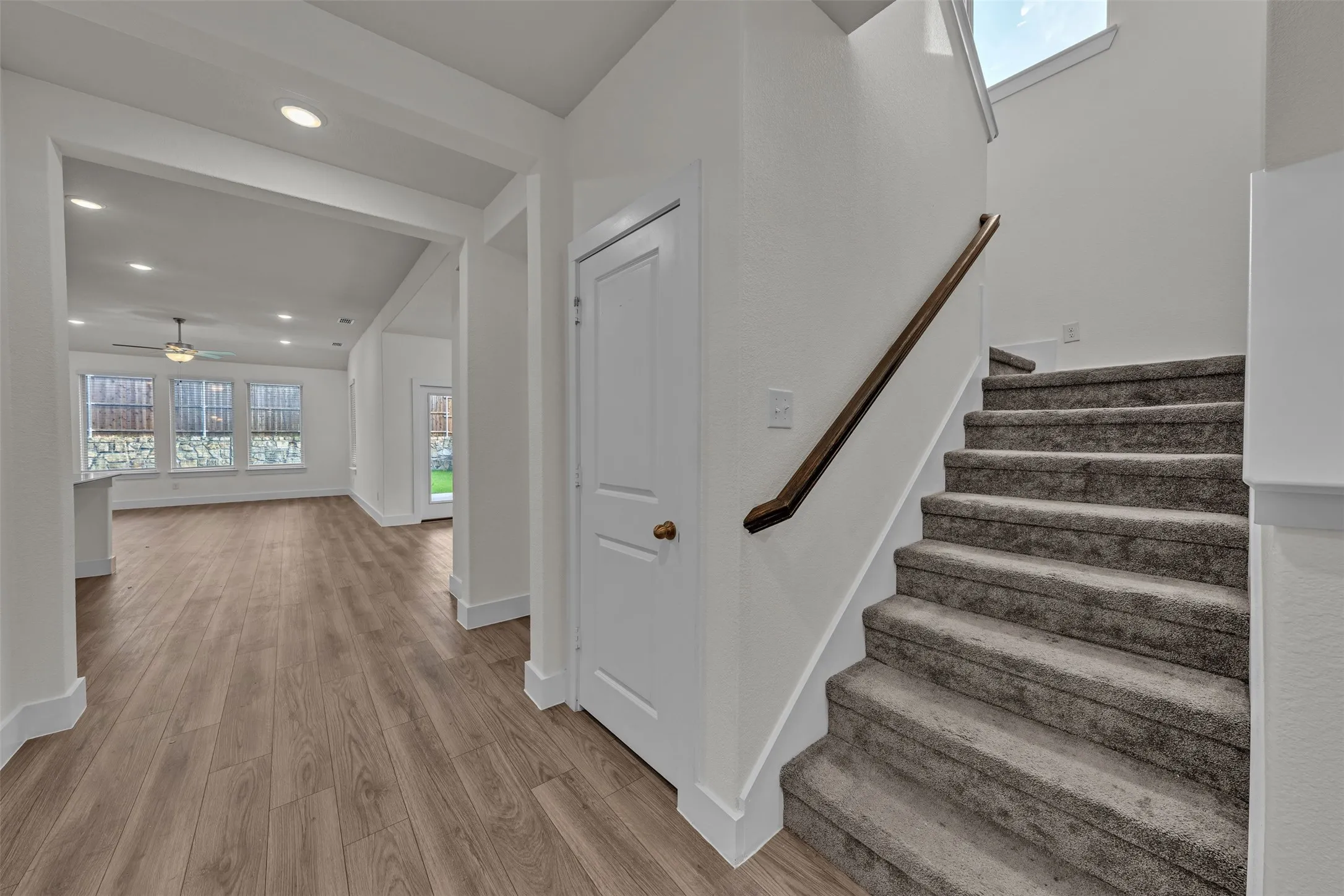 Staircase at 5149 Cantle Ct in Fort Worth, Texas, Tarrant County, with light colored carpet and stained wood railing. Large window for natural light on landing.