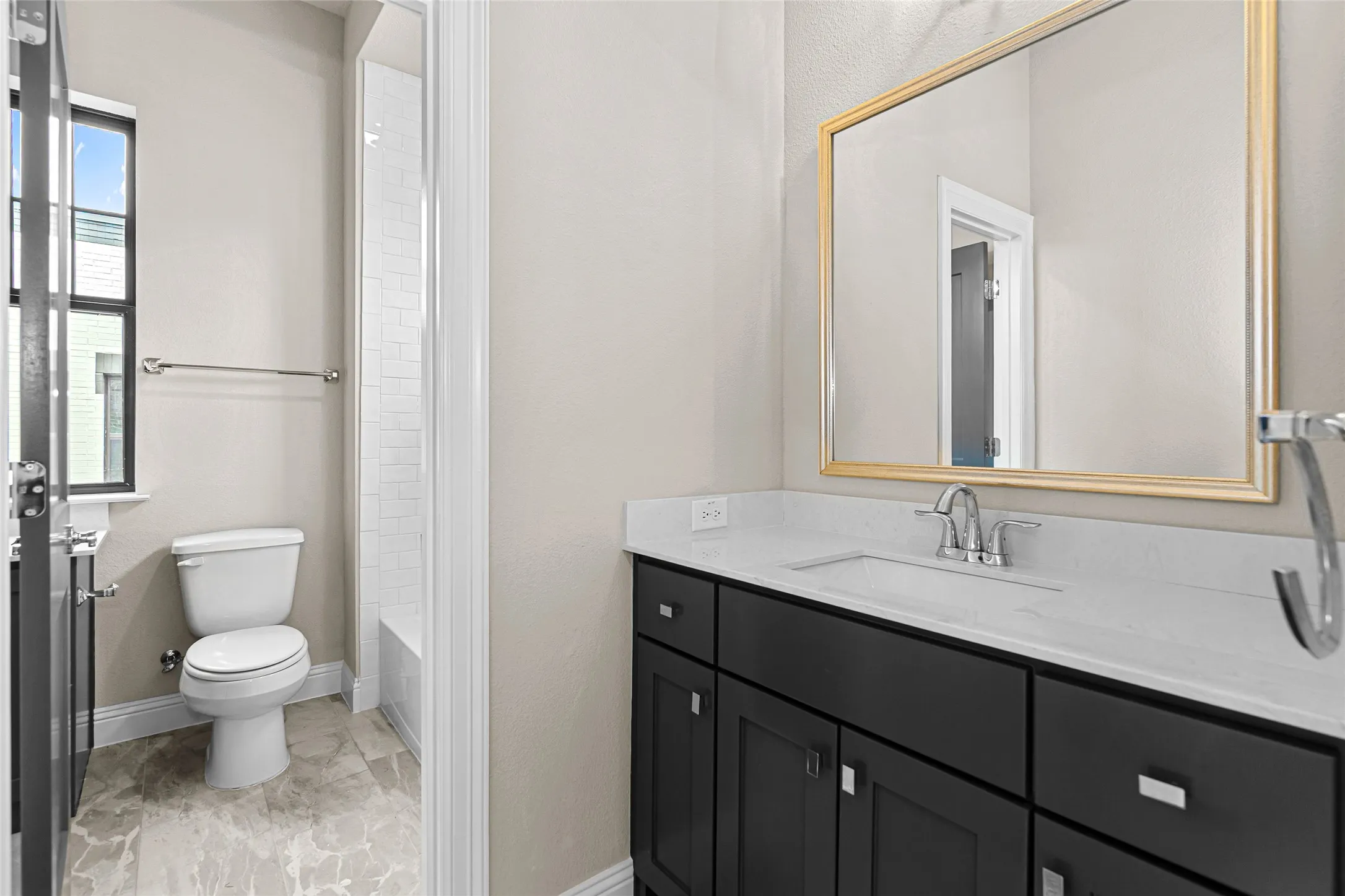 Bathroom featuring a dark wood-finish vanity with a light countertop, a rectangular undermount sink, and a gold-framed mirror. Jack and Jill Bathroom