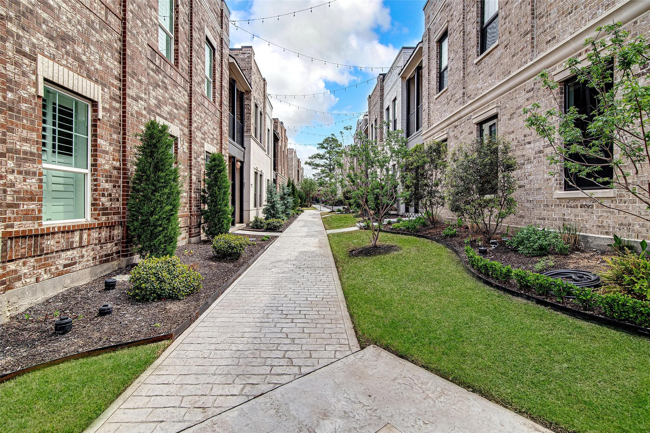 Stamped concrete walkway bordered by manicured lawns and mature landscaping