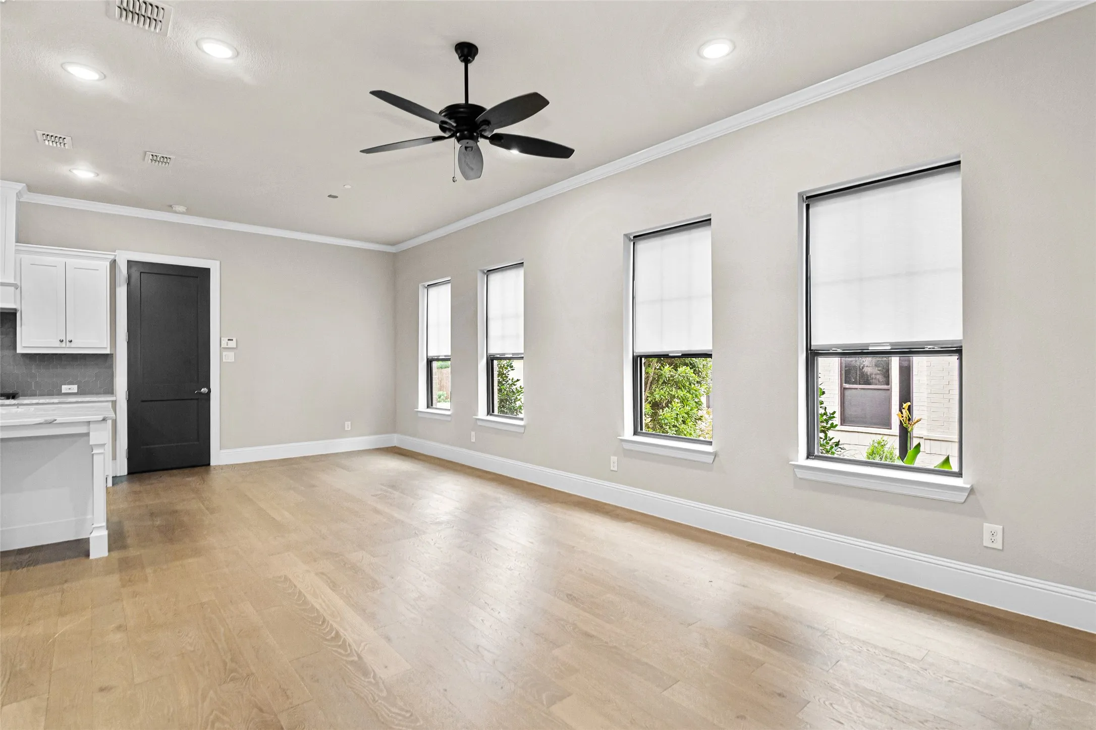 Spacious open-concept living area featuring wood-finish flooring, recessed lighting, and a ceiling fan
