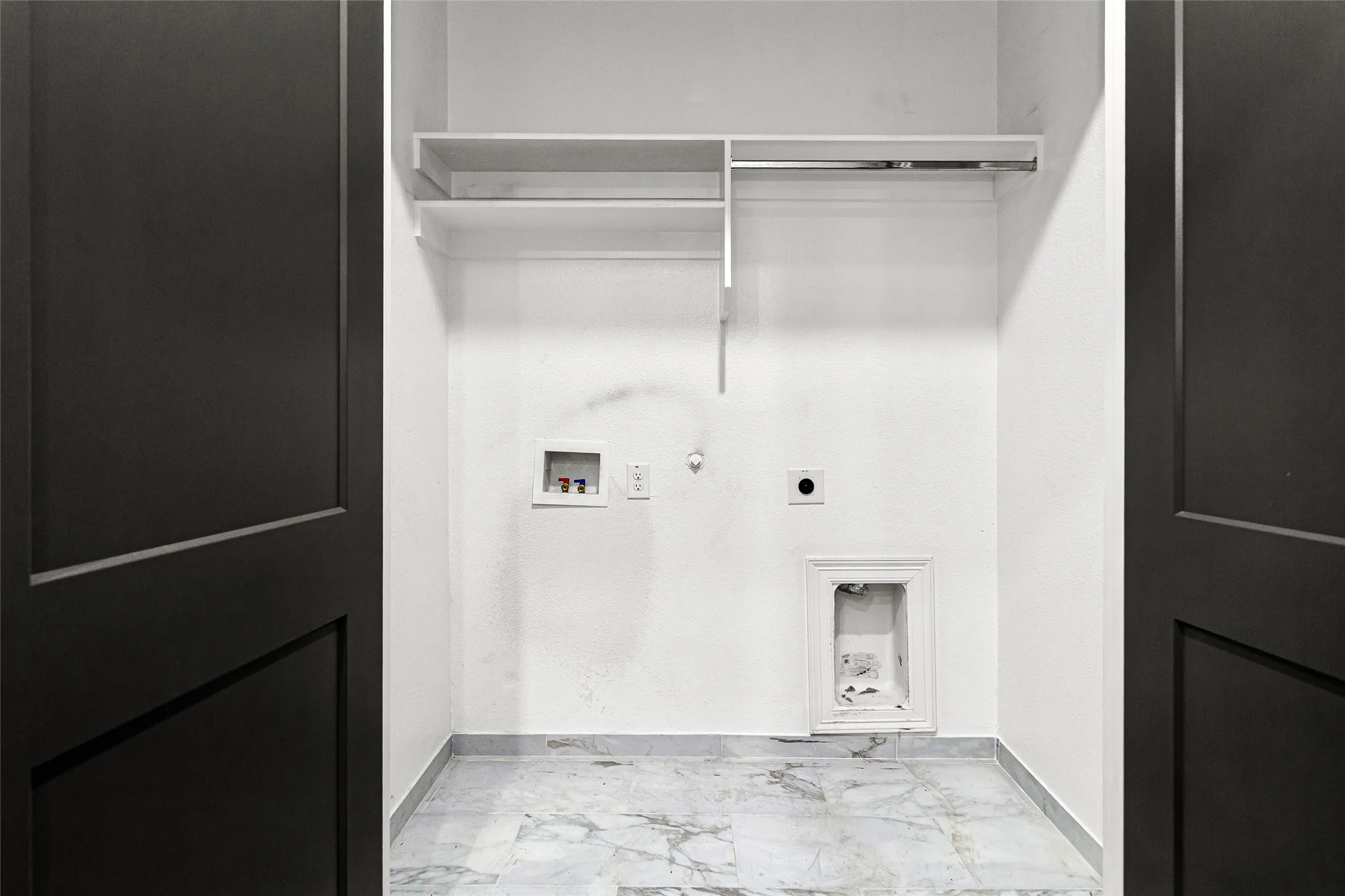 Dedicated utility space featuring marble-look tile flooring and white painted walls