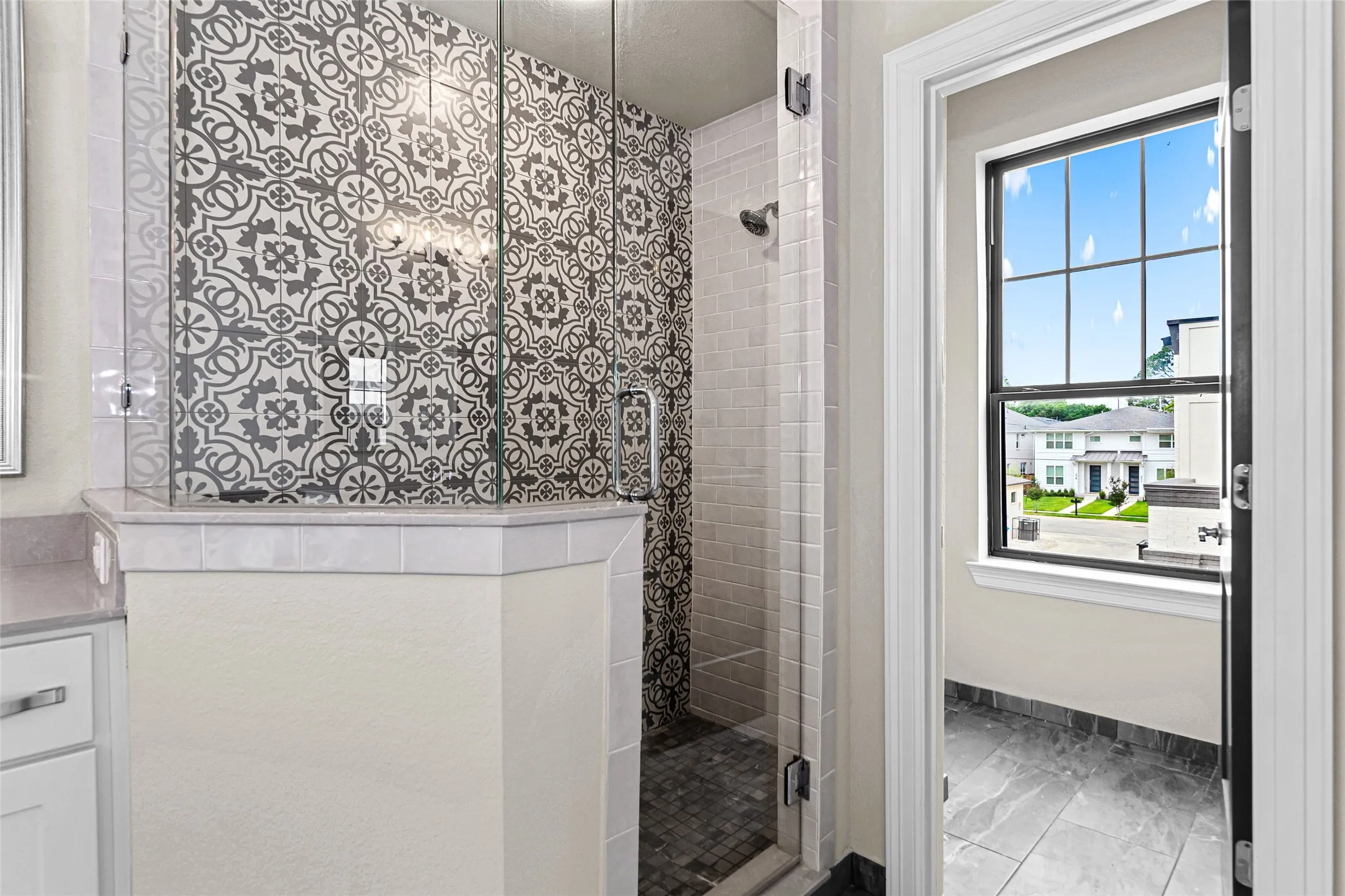 2nd floor primary bathroom. Walk-in shower featuring patterned wall tile, clear glass enclosure, and a tiled shower pan