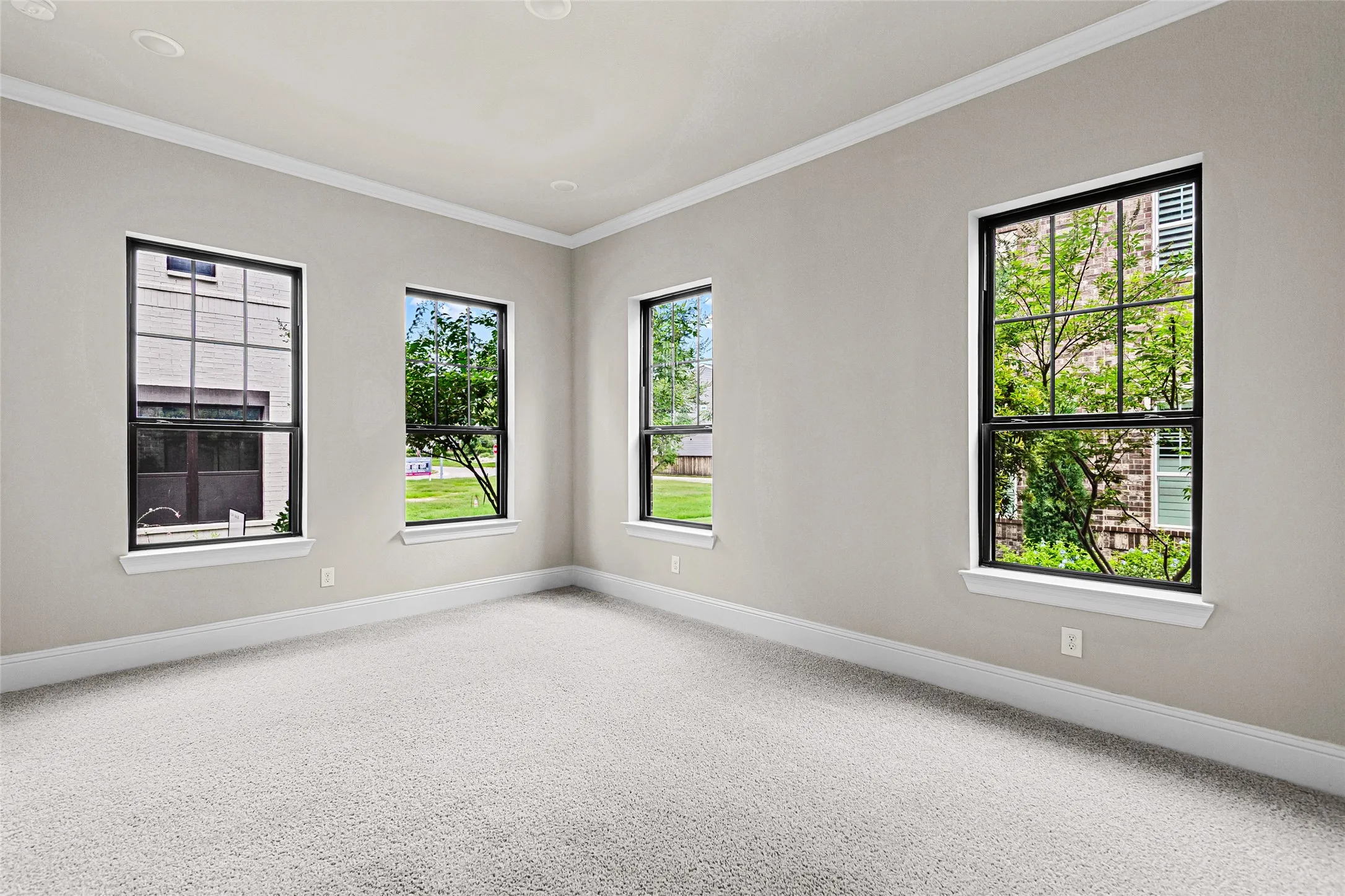 Primary Suite on the first floor, Neutral-toned room with three large windows featuring black frames and white sills