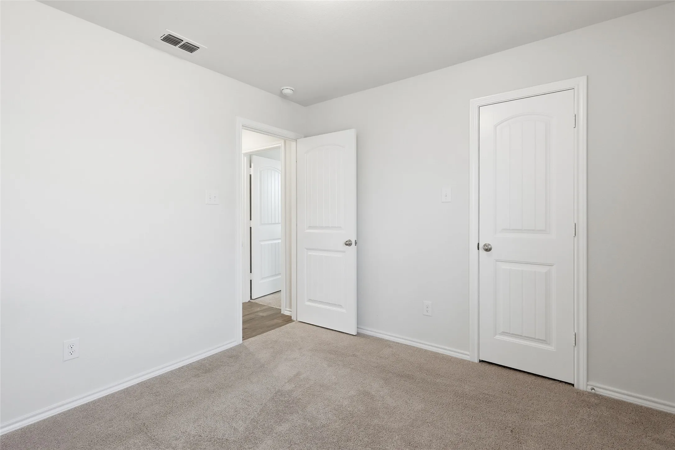 Neutral-toned carpeting extends throughout this interior space, featuring white walls and trim