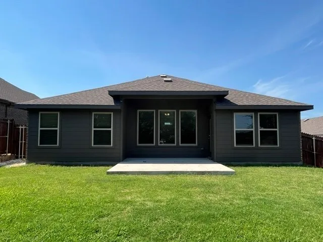 Rear exterior featuring dark gray siding, a concrete patio, and a shingled roof