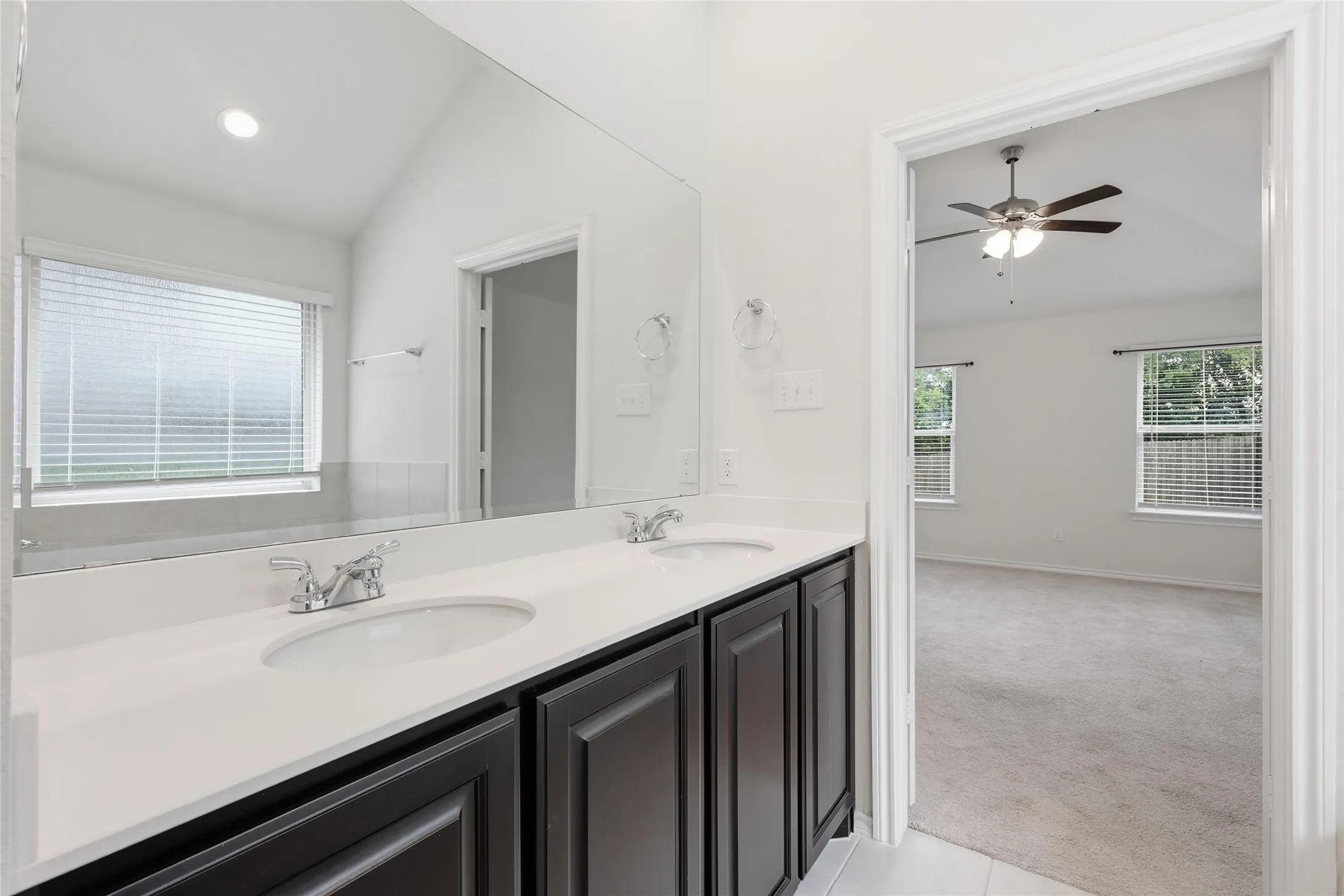 Dual sink vanity with dark wood-finish cabinetry and a white countertop