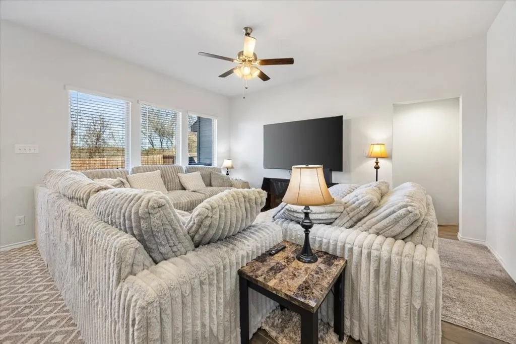Bright open-concept living area with multiple windows, recessed lighting, and a ceiling fan