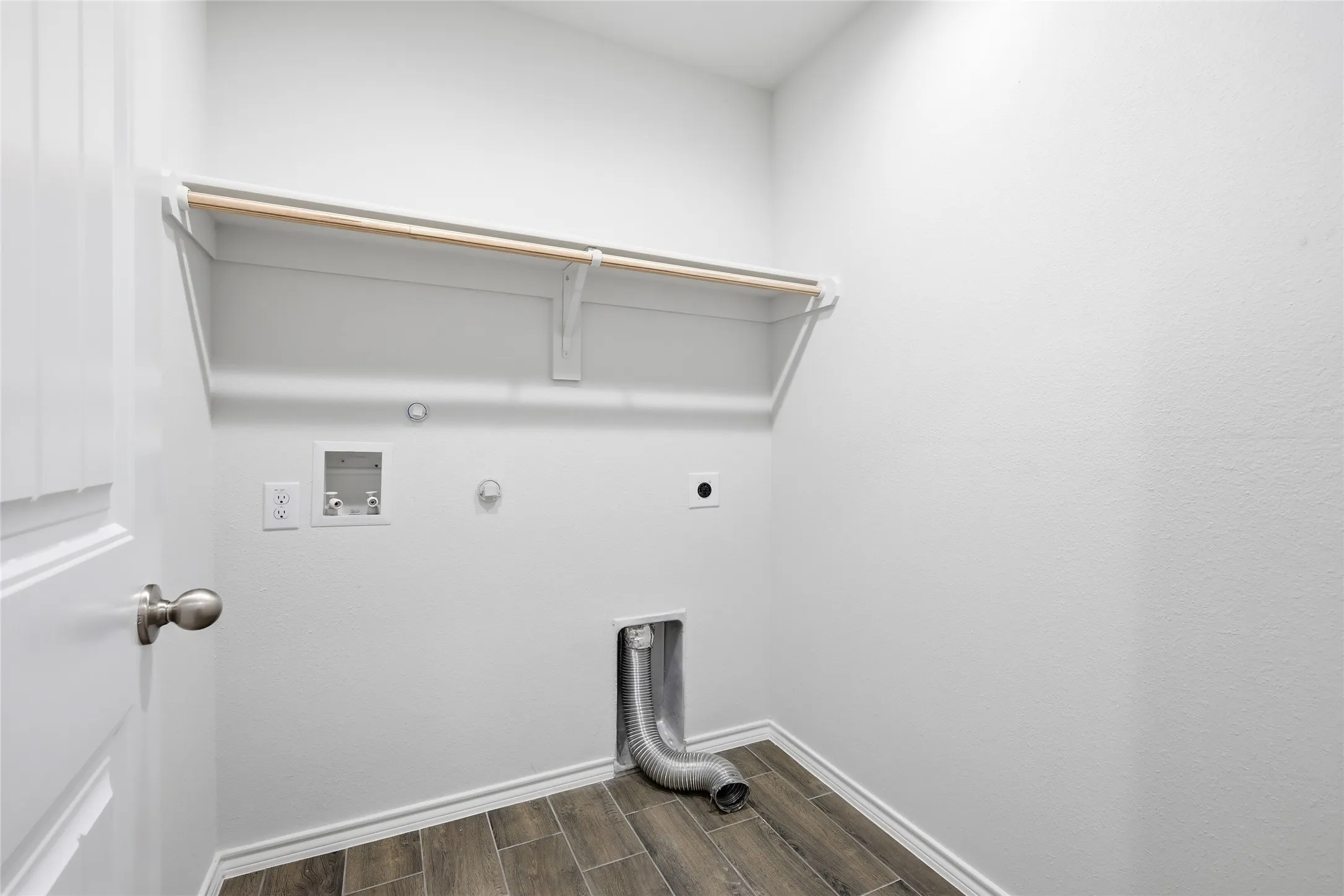 Dedicated utility space featuring wood-look tile flooring, white walls, and a built-in shelving unit with a hanging rod