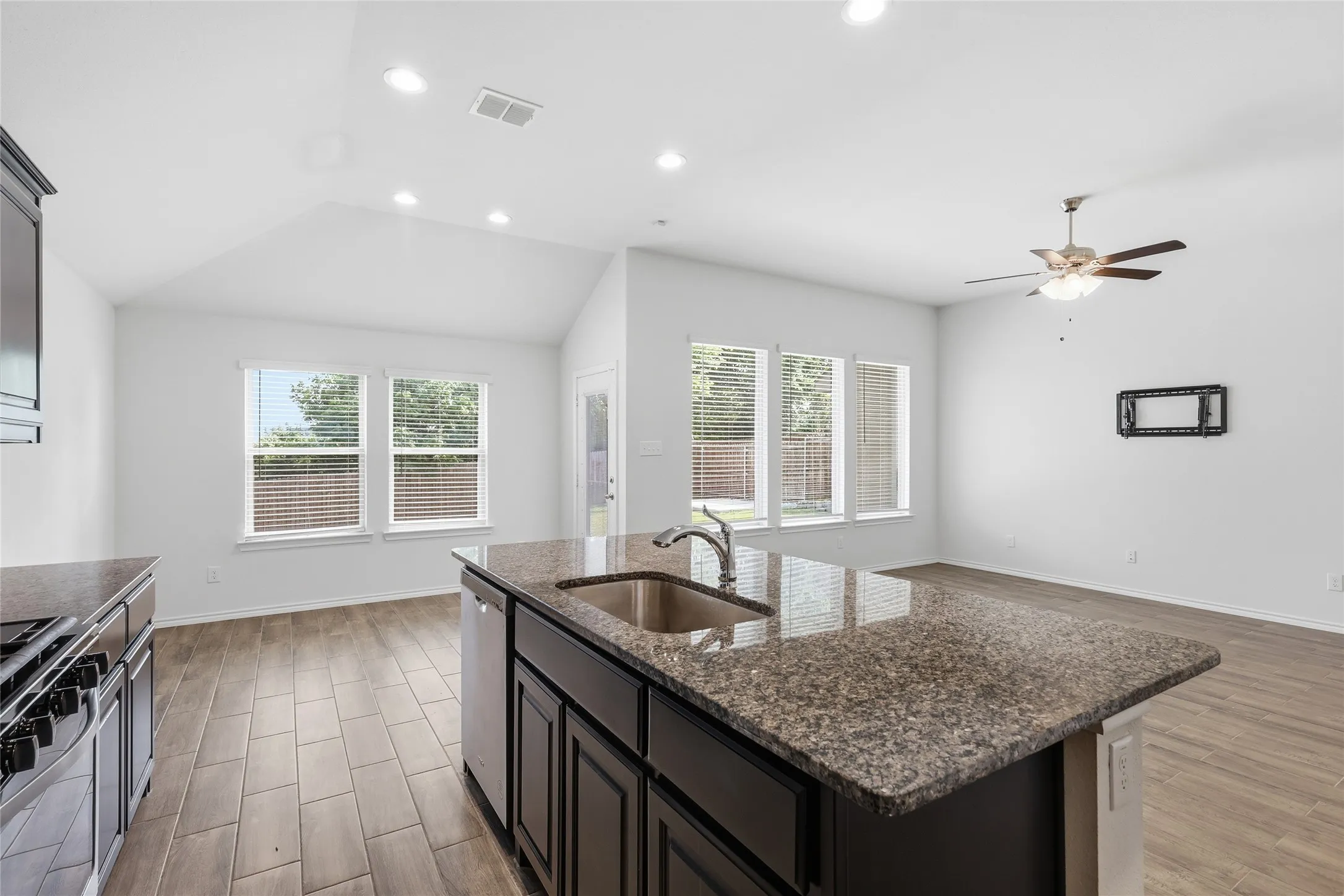 Kitchen island featuring a double basin sink, integrated dishwasher, and a stone-finish countertop